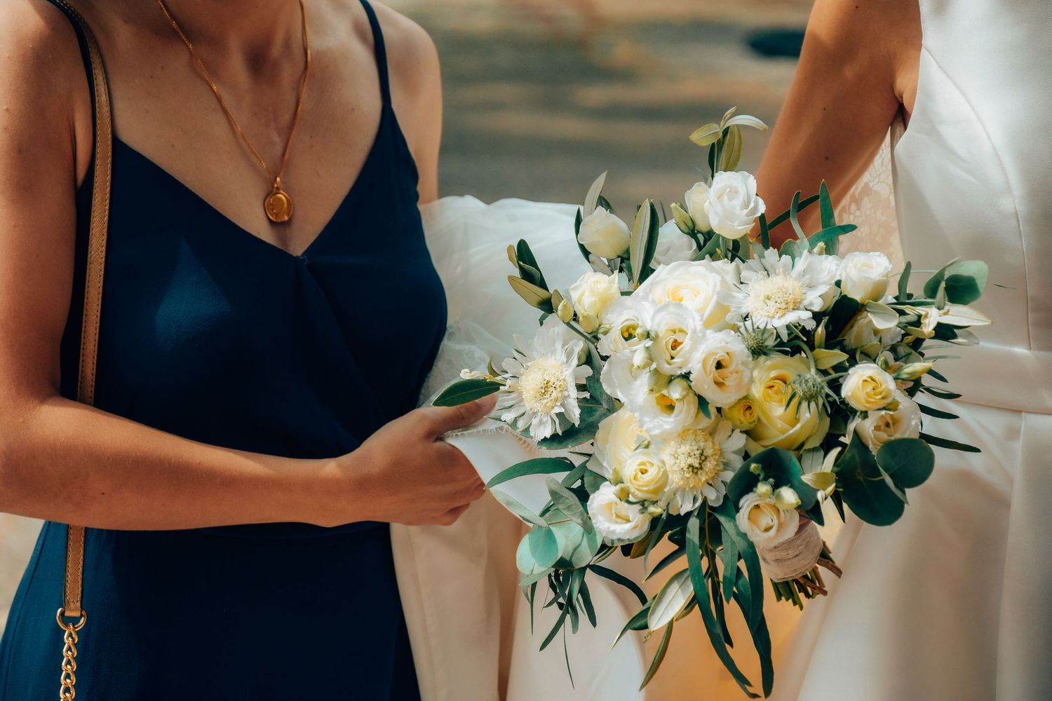 Wedding party members holding elegant white and yellow flower bouquets.