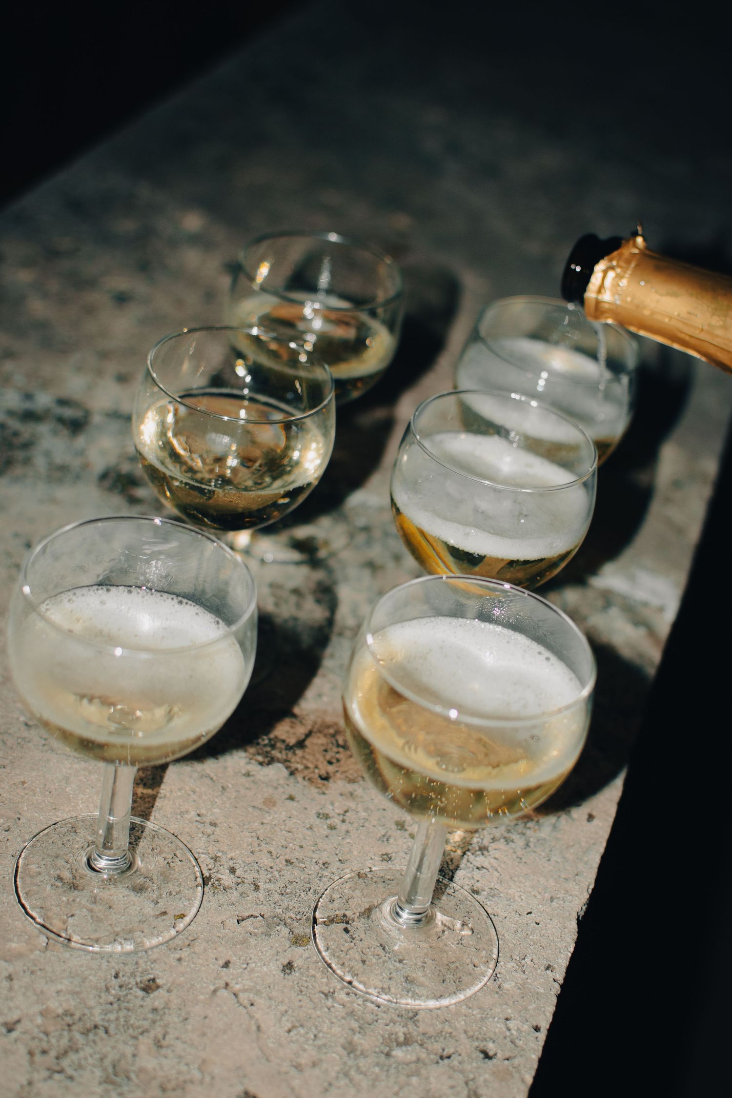Several champagne glasses filled with bubbly drinks on a textured surface.