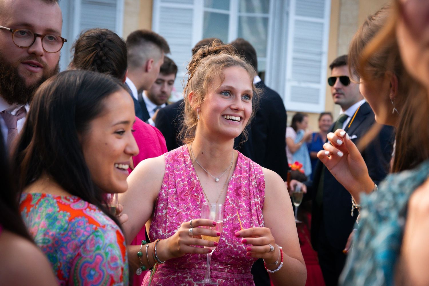 Guests sharing laughter and drinks at an outdoor wedding reception.