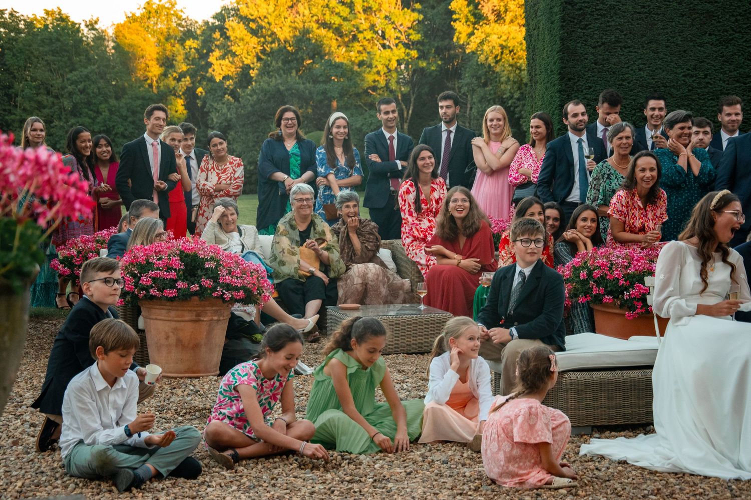 Wedding guests gathered on garden steps during golden hour.