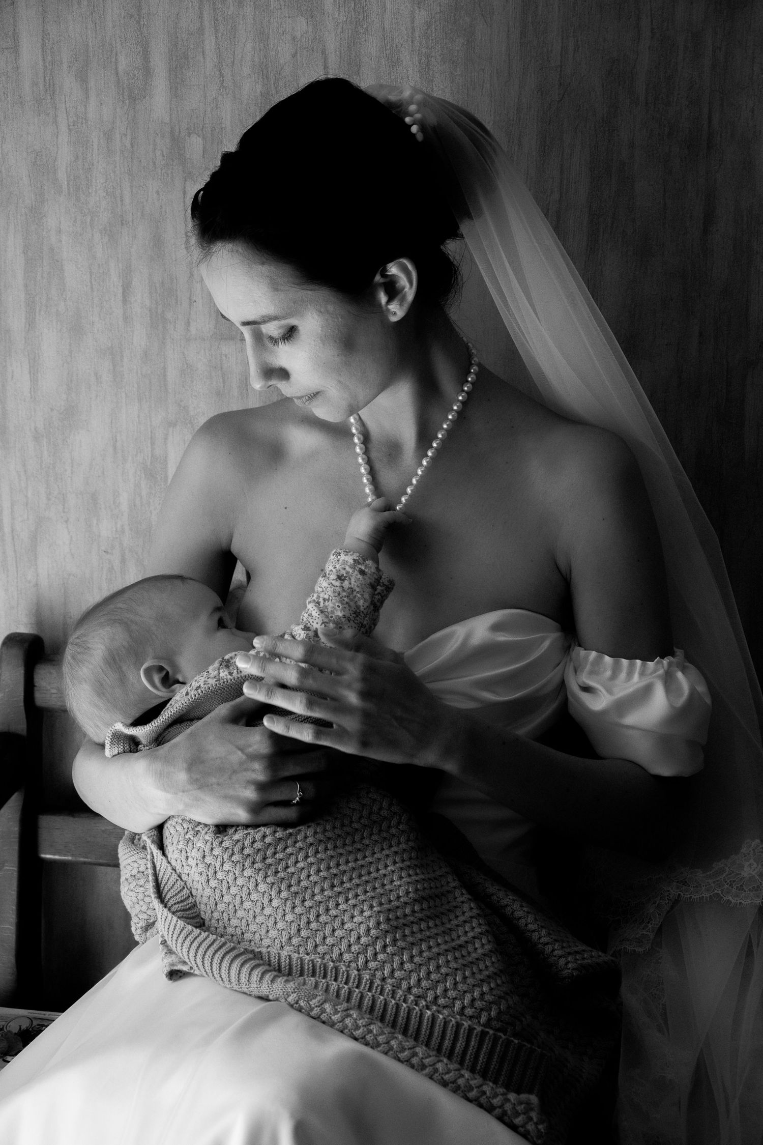 A series of intimate black and white photos showing a mother in wedding attire gently nursing a baby in profile view.