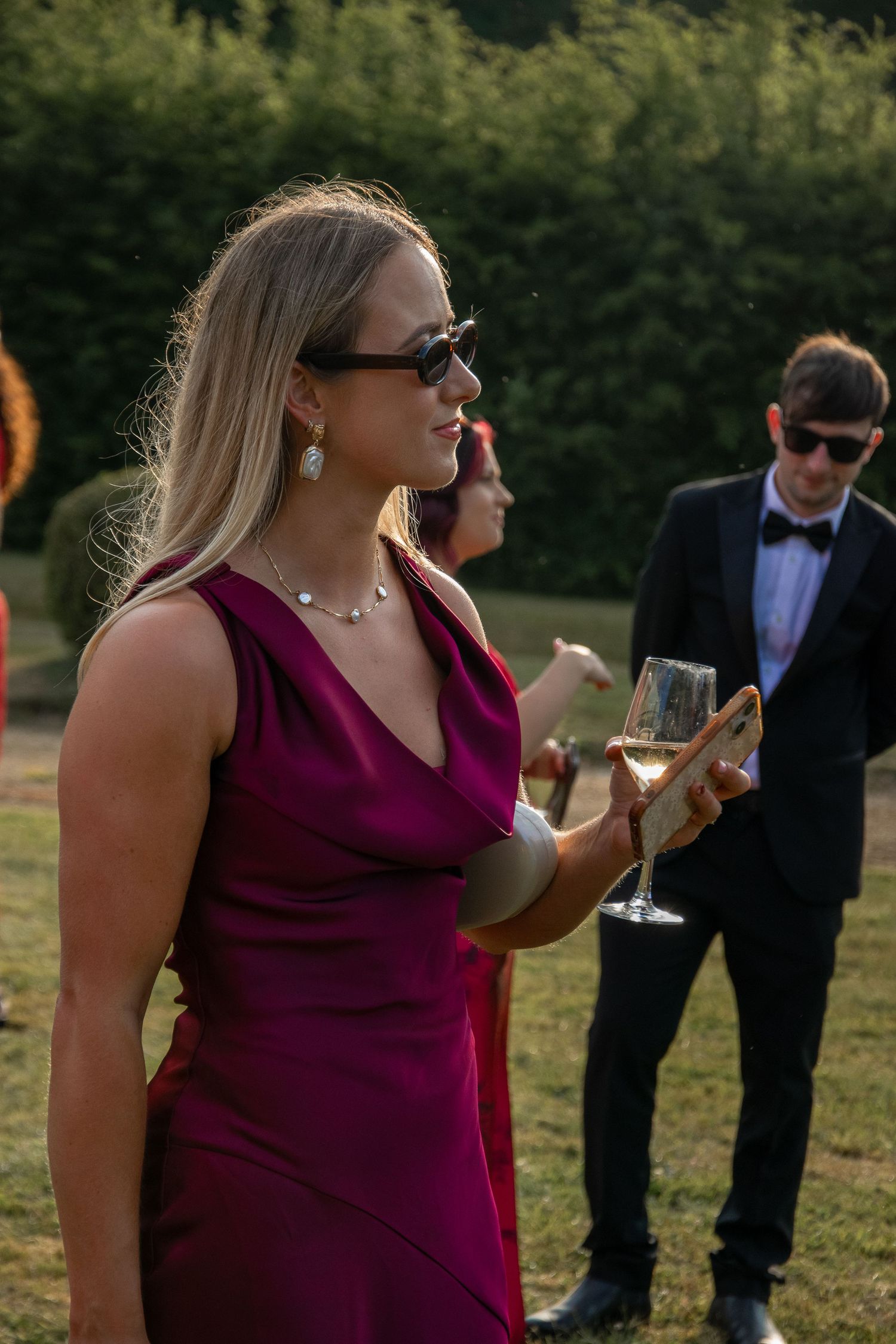 Woman in burgundy dress stands outdoors while multiple images show her walking and talking at what appears to be an event.