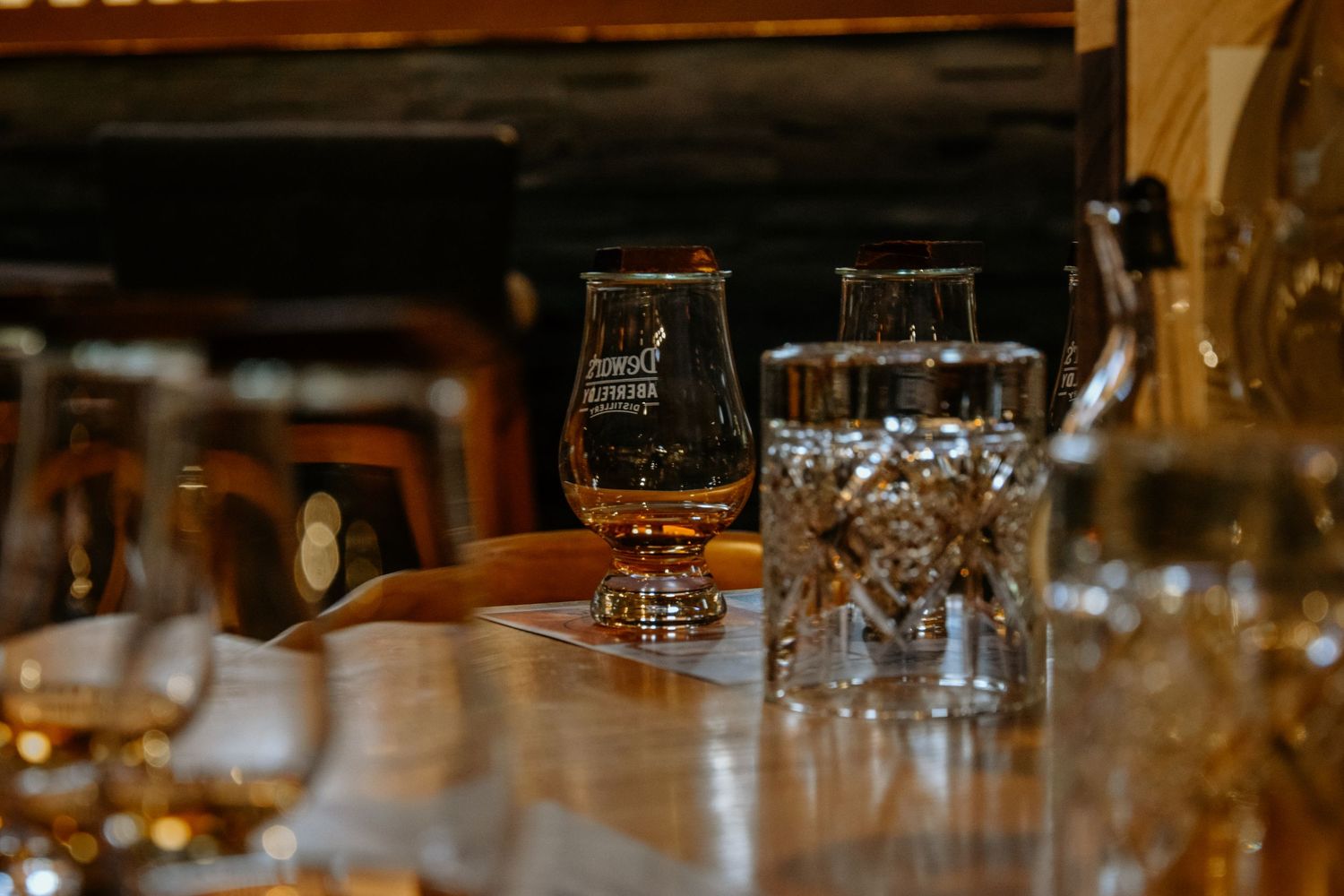 Crystal glassware for spirits tasting set up on a wooden bar counter.