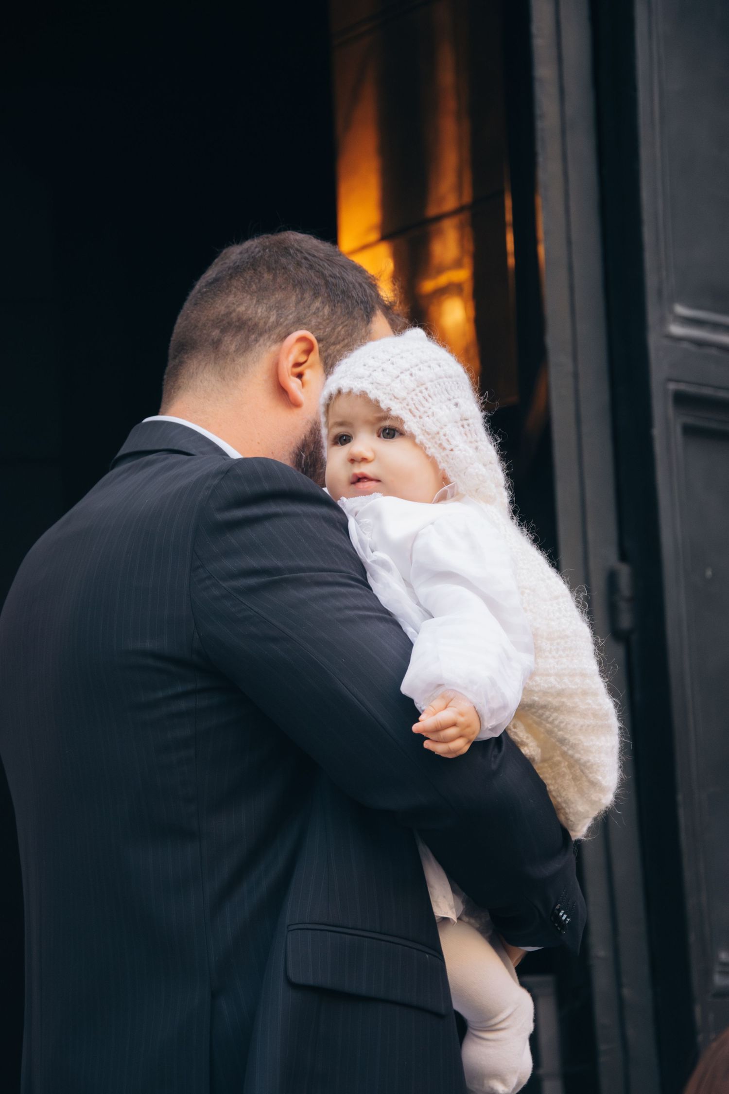 A formal scene with a small child wearing white winter clothing.