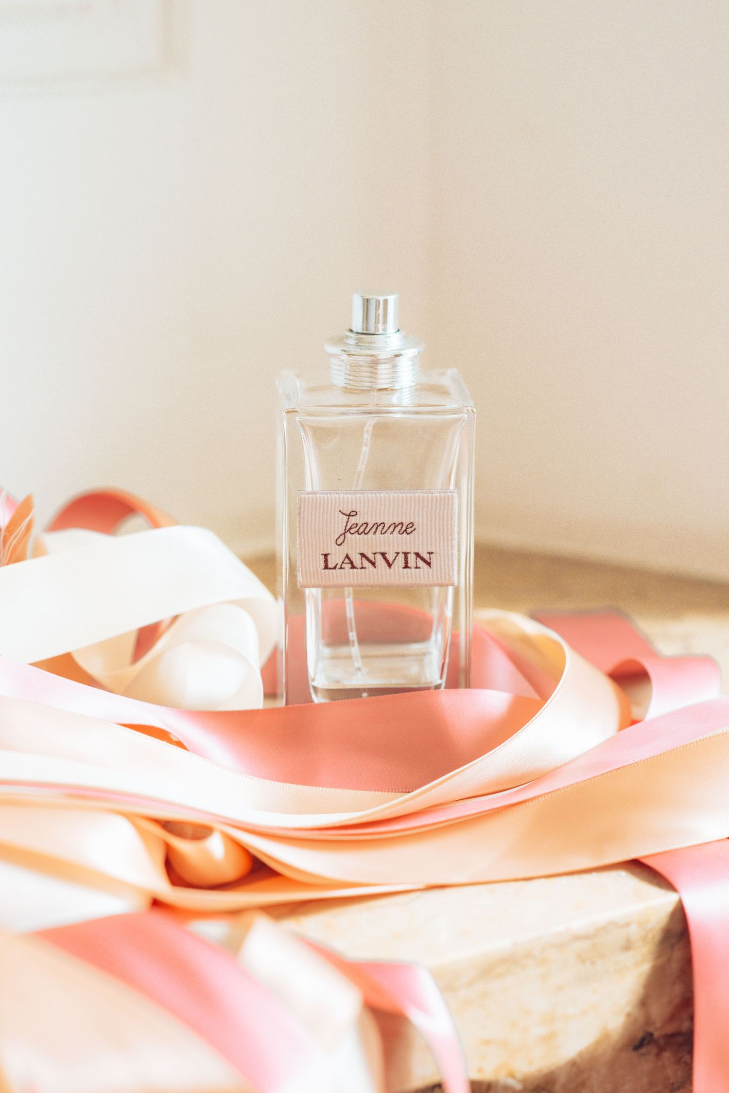 Lanvin perfume bottle elegantly placed on pink silk fabric in soft lighting.