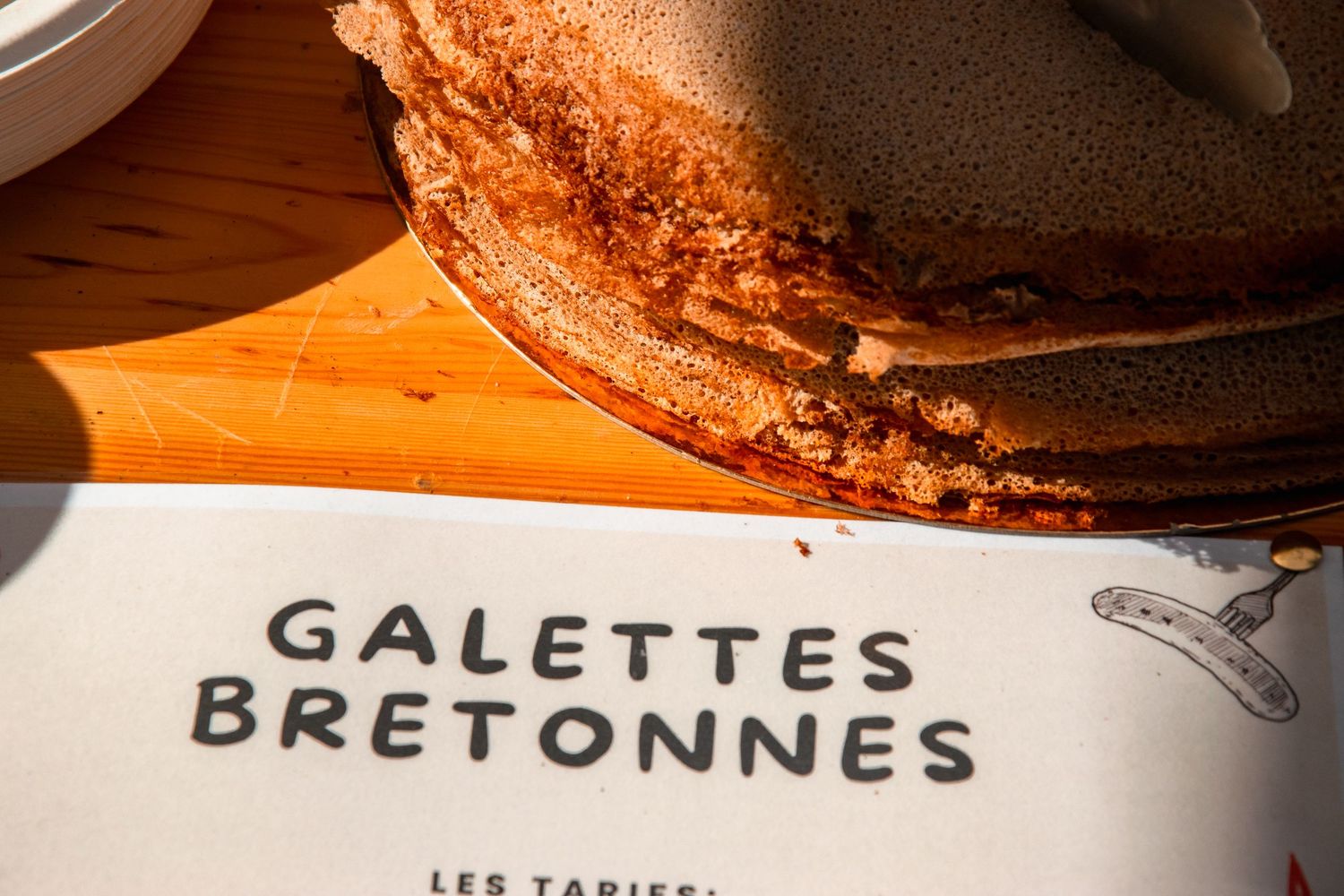 Close-up of traditional French galettes bretonnes with text visible on menu or placemat.