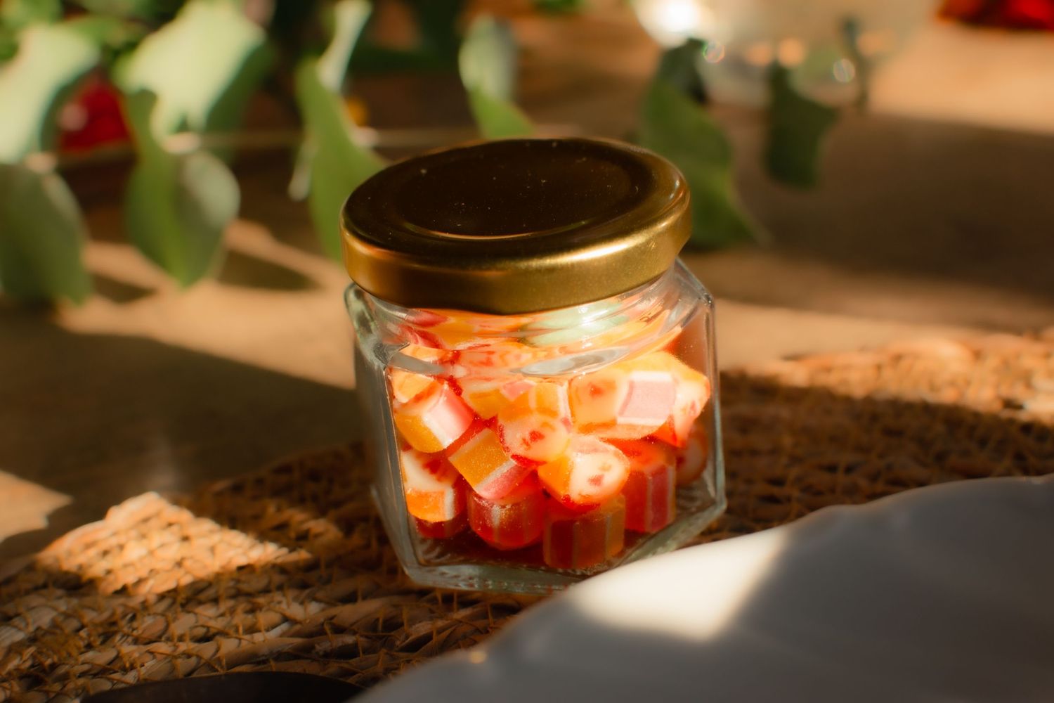 A decorative jar filled with colorful candy pieces lit by natural sunlight.