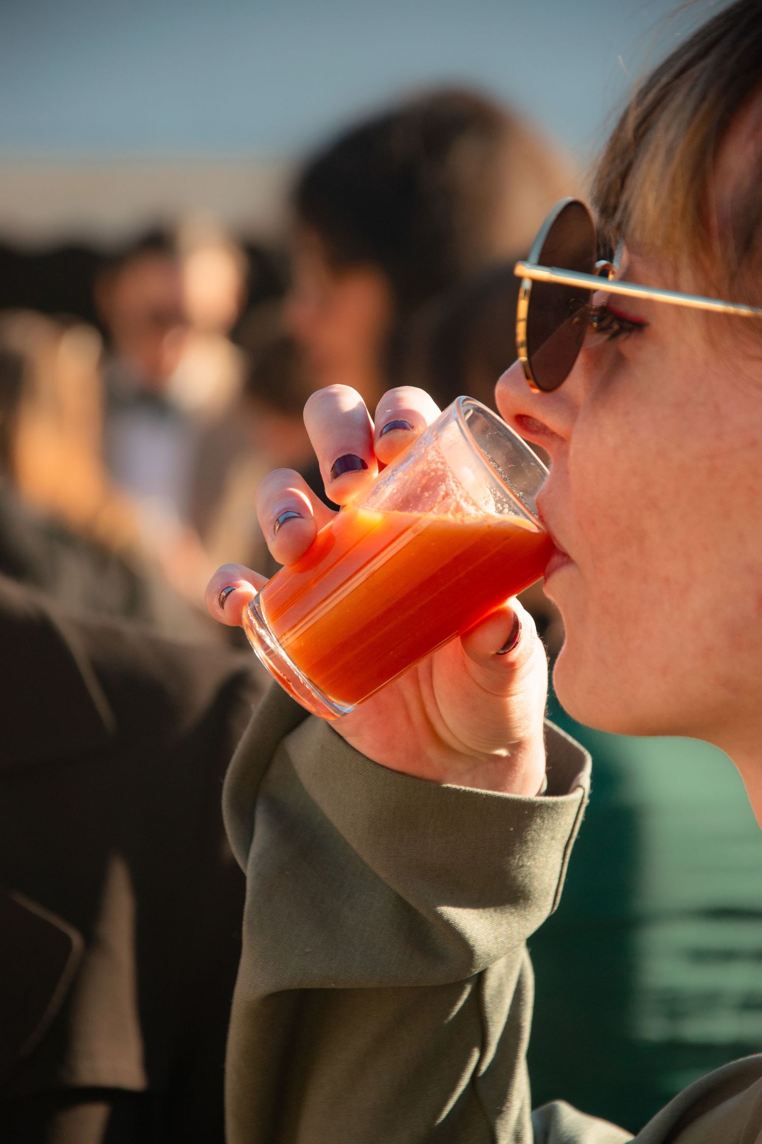 Orange cocktail being sipped from a glass in outdoor lighting.