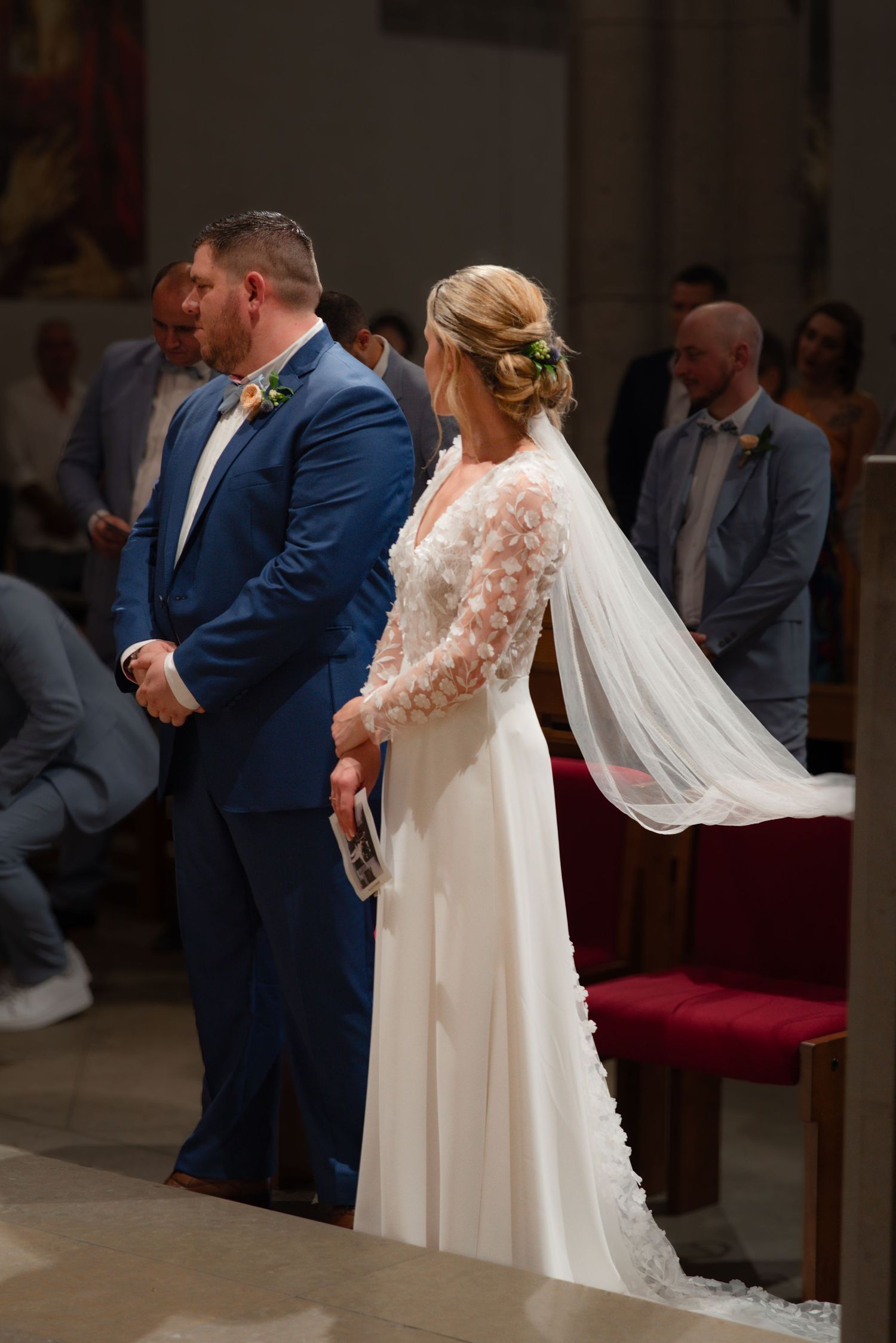 Traditional wedding ceremony in church with elegant bridal gown and blue suit.