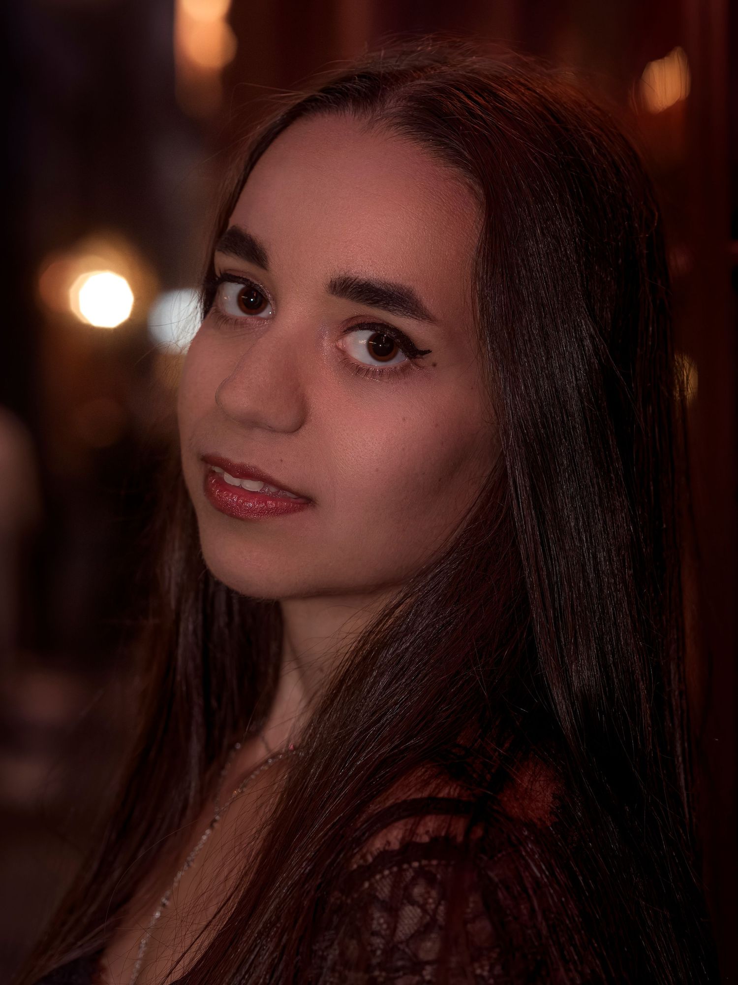 A portrait series in moody lighting shows a person with long dark hair and makeup against a warm bokeh background.