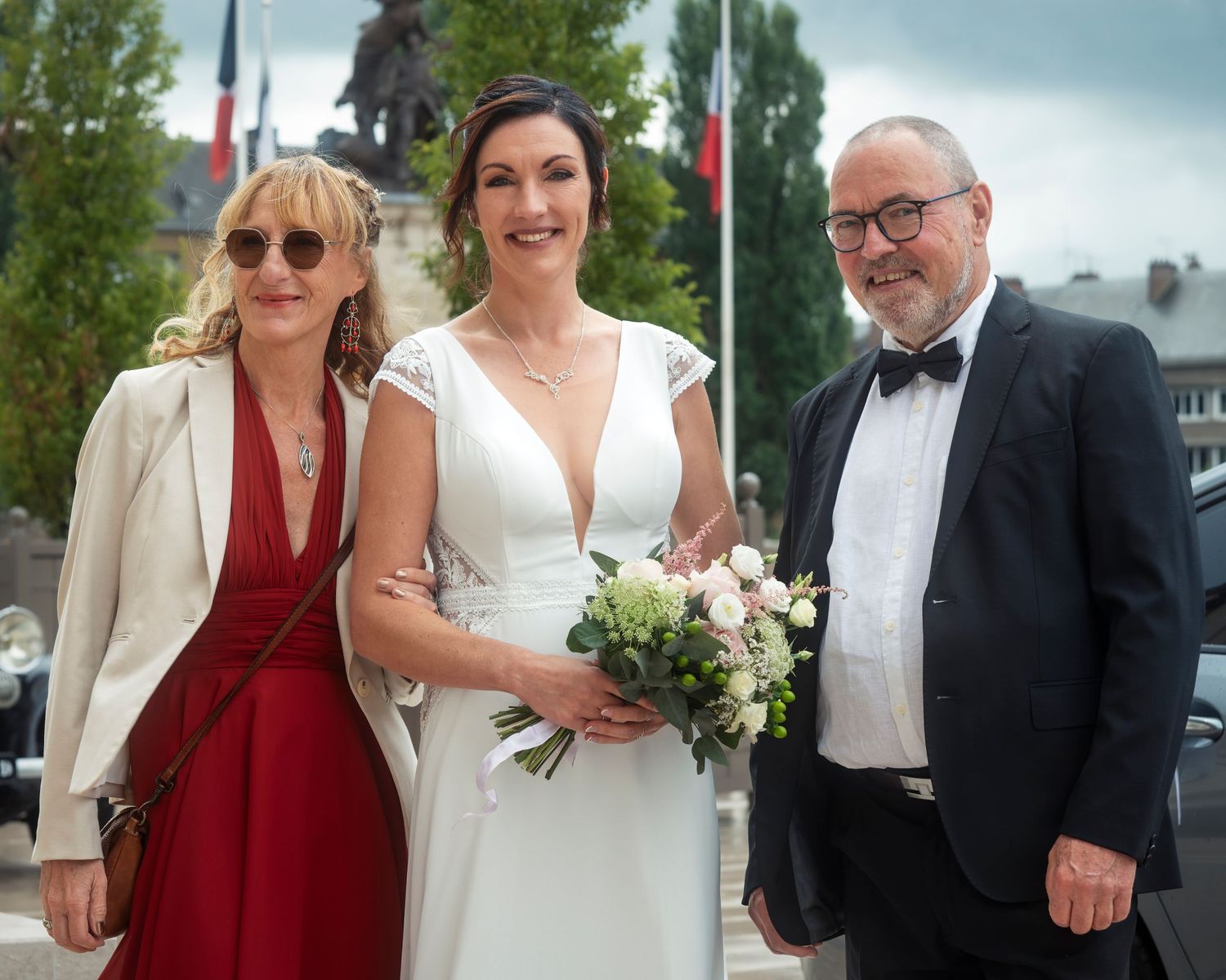 Wedding party members in burgundy and white attire pose together outdoors during a celebration.