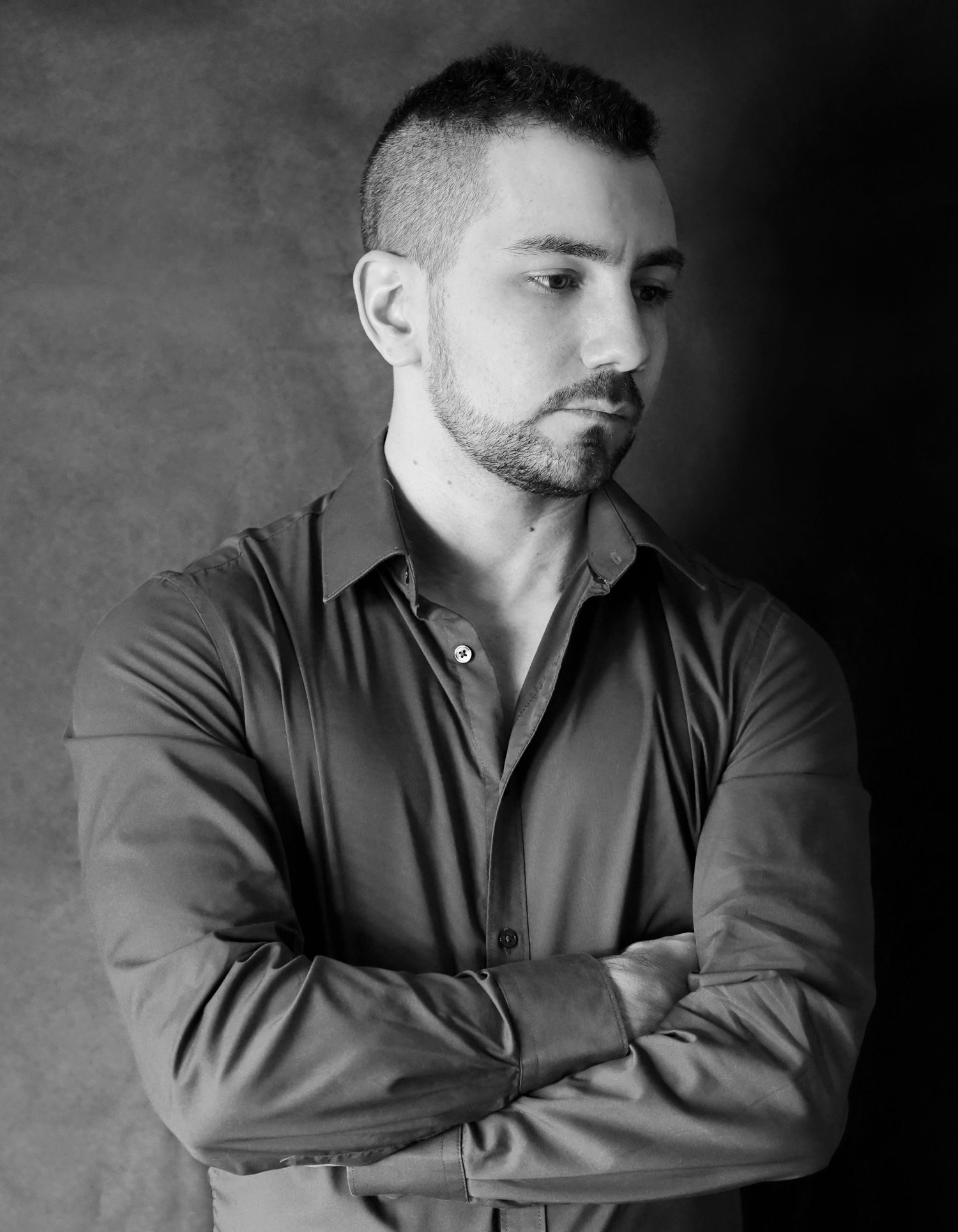 Black and white portrait of a person in professional attire against a dark background.