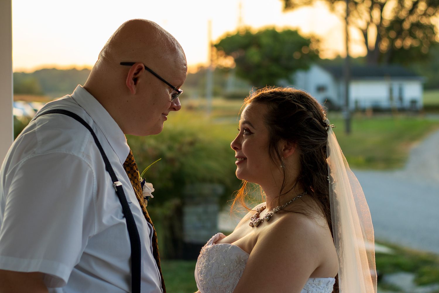 A sunset wedding ceremony moment as two people share an intimate gaze outdoors.