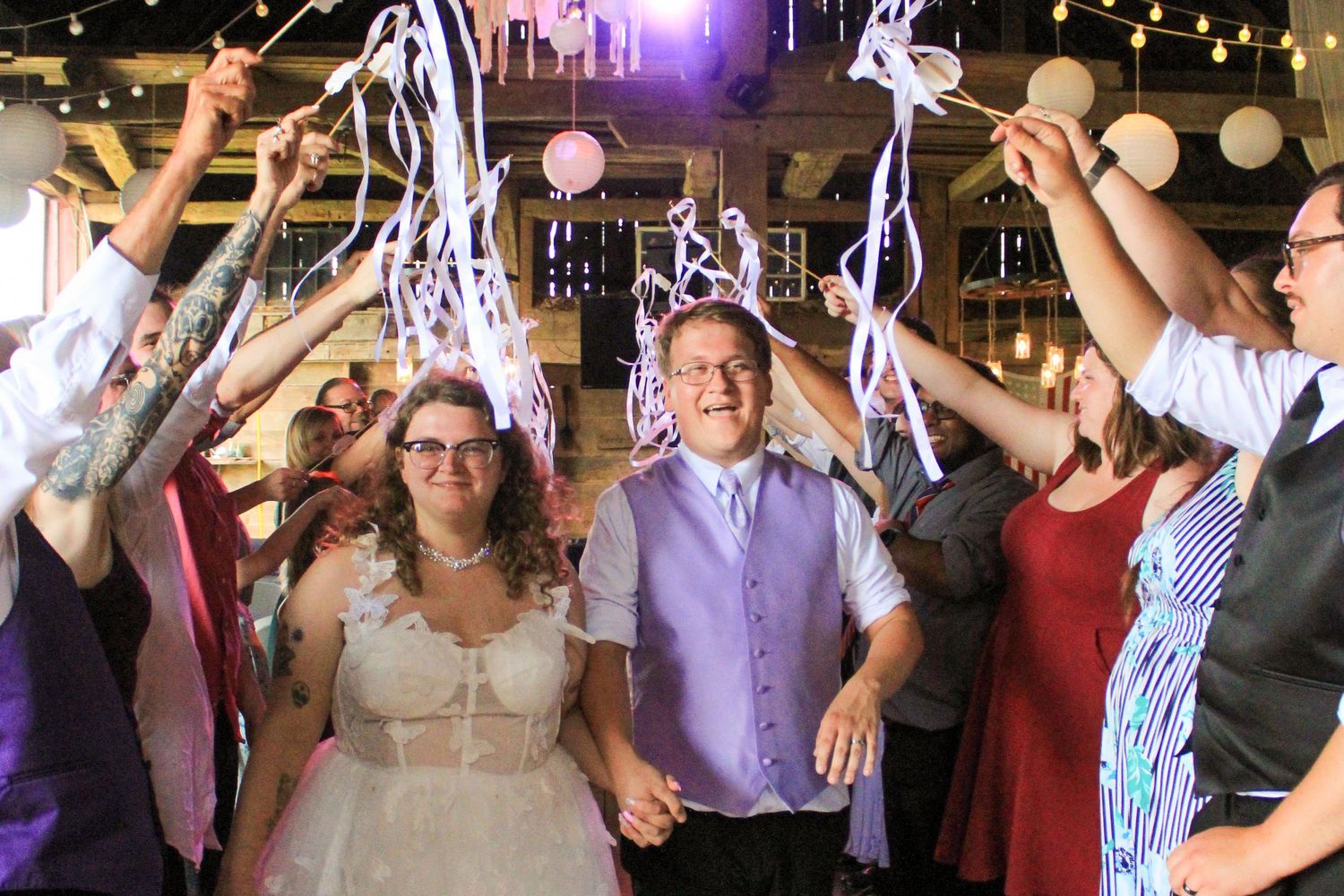 Wedding party celebrates with streamers and lights on the dance floor during a joyful reception celebration.