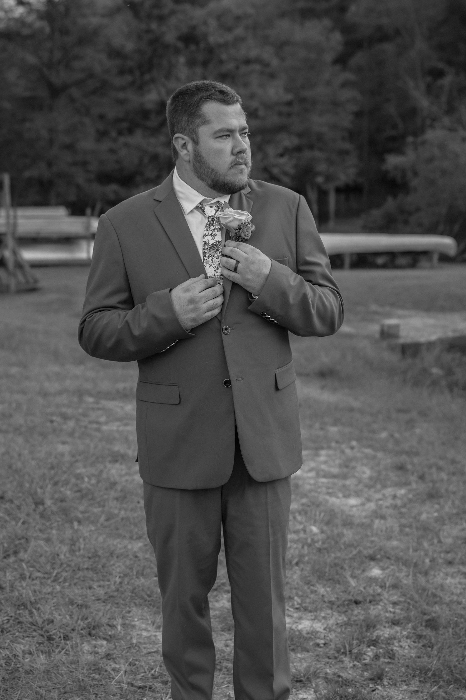 Black and white portrait of groom in suit reading letter during wedding first look.