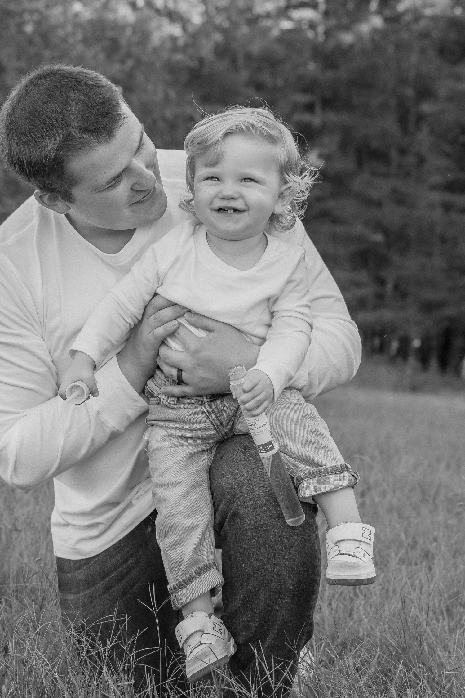 Black and white photo sequence showing a playful interaction between parent and child outdoors in a grassy field.