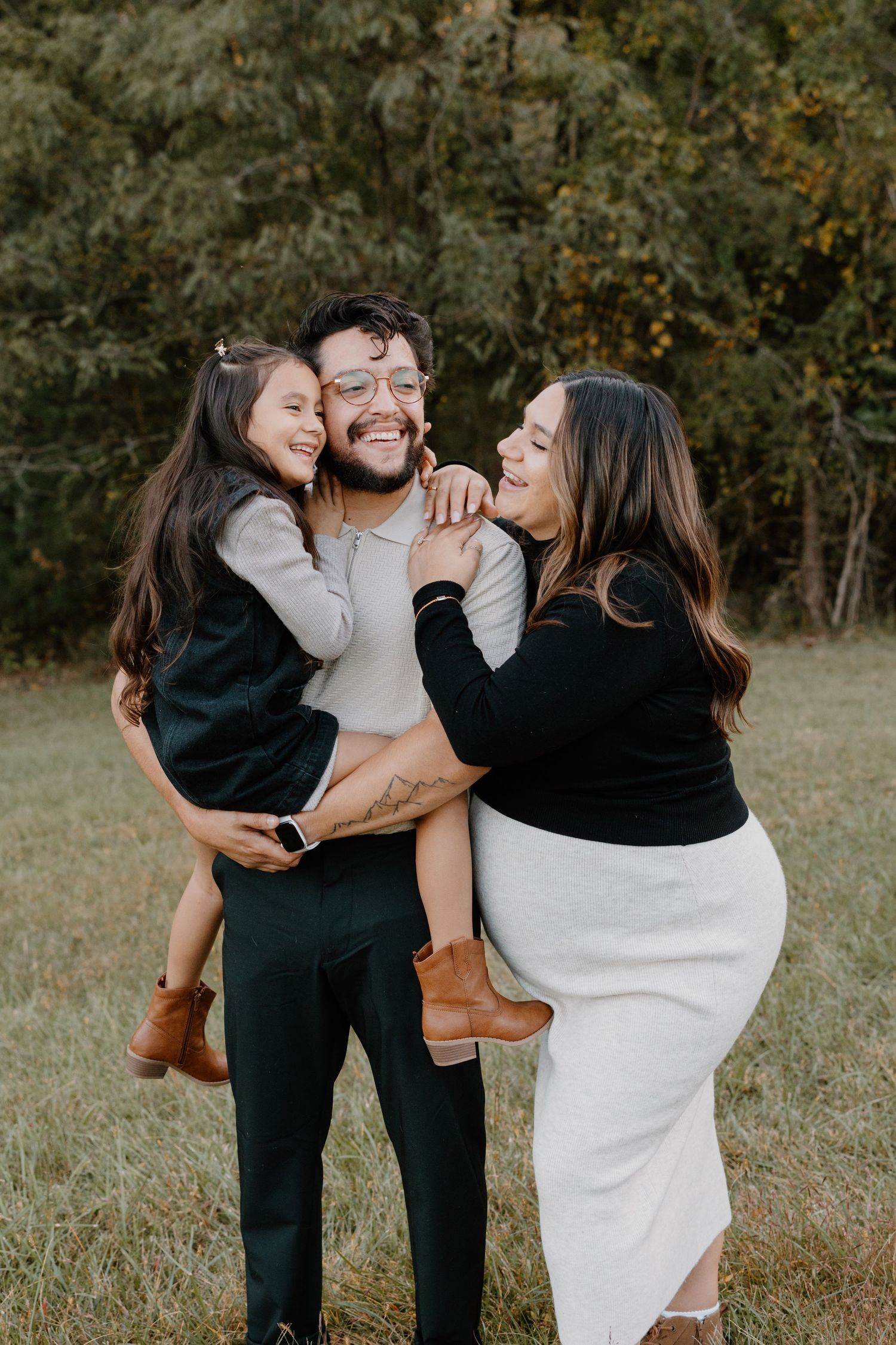A joyful family embraces and laughs together during an outdoor autumn photoshoot.