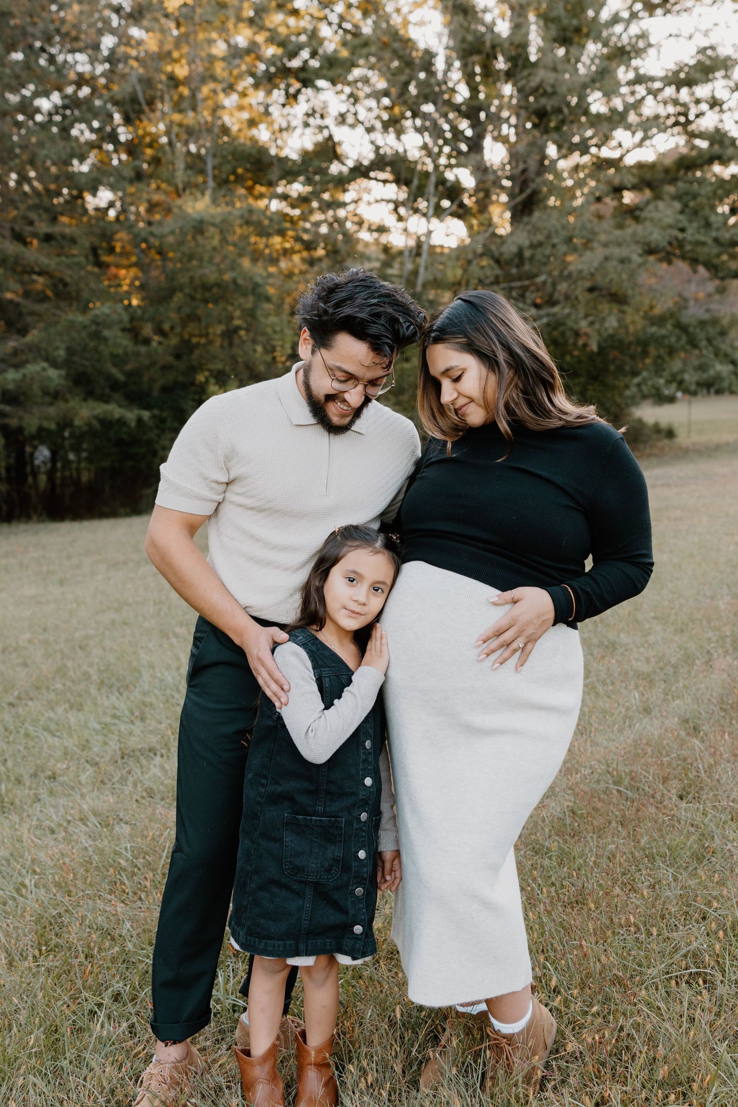 A loving family shares tender moments together in a grassy field during golden hour.