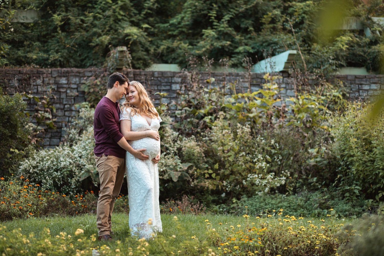 A couple shares an intimate moment in a lush garden filled with vibrant yellow wildflowers and greenery.