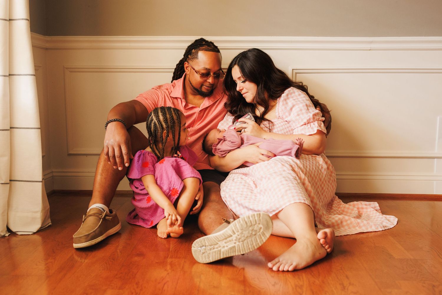 A series of four connected photos showing tender family moments on a hardwood floor.