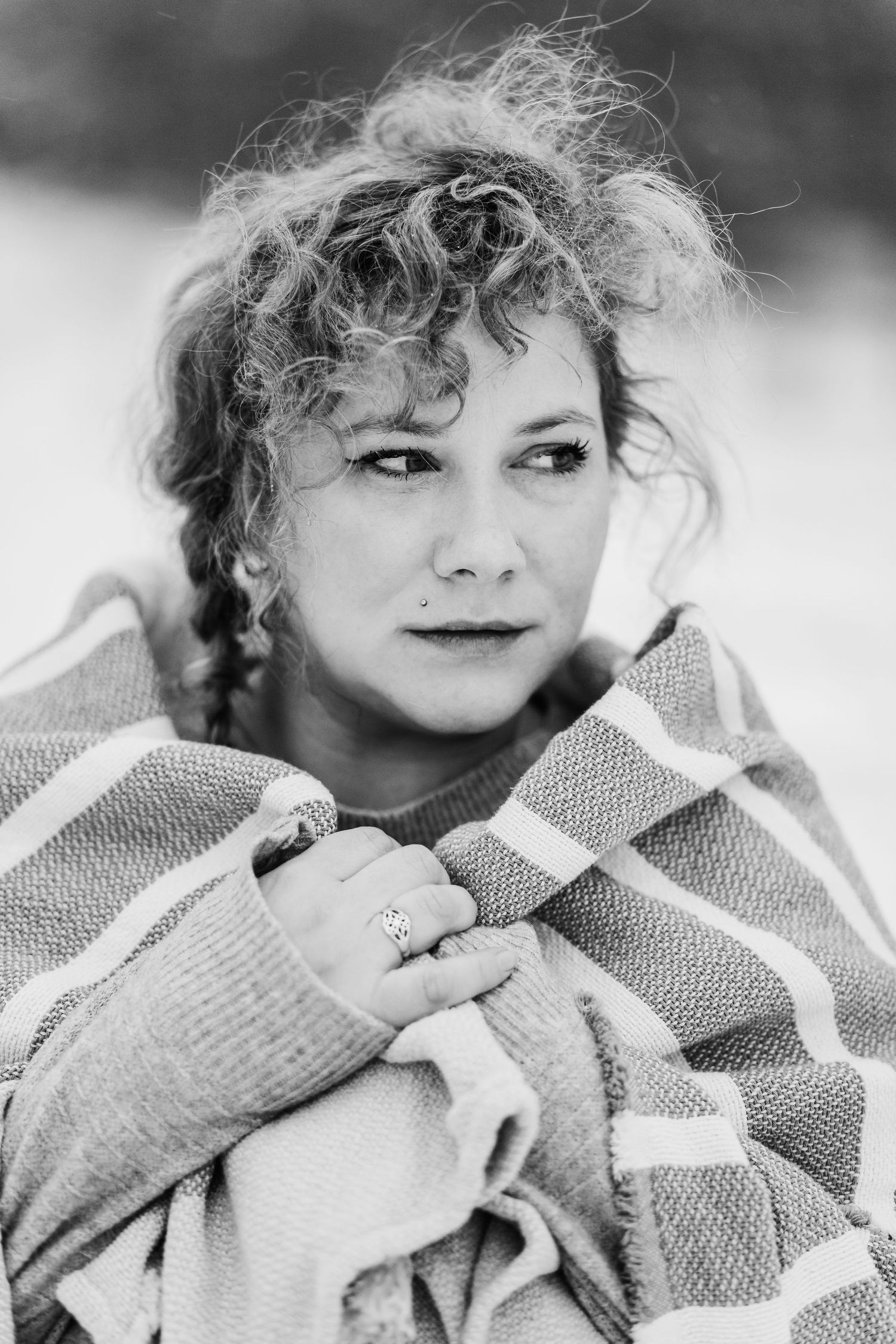 Artistic black and white portrait wrapped in striped blanket during winter photoshoot.
