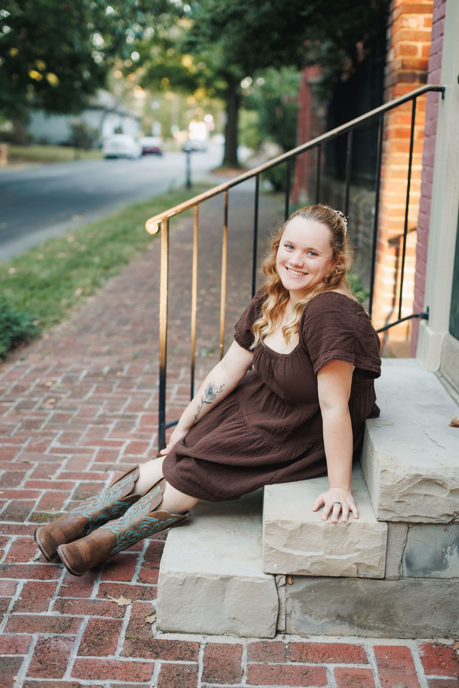 Outdoor portrait on brick steps with brown dress and cowboy boots in warm autumn lighting.