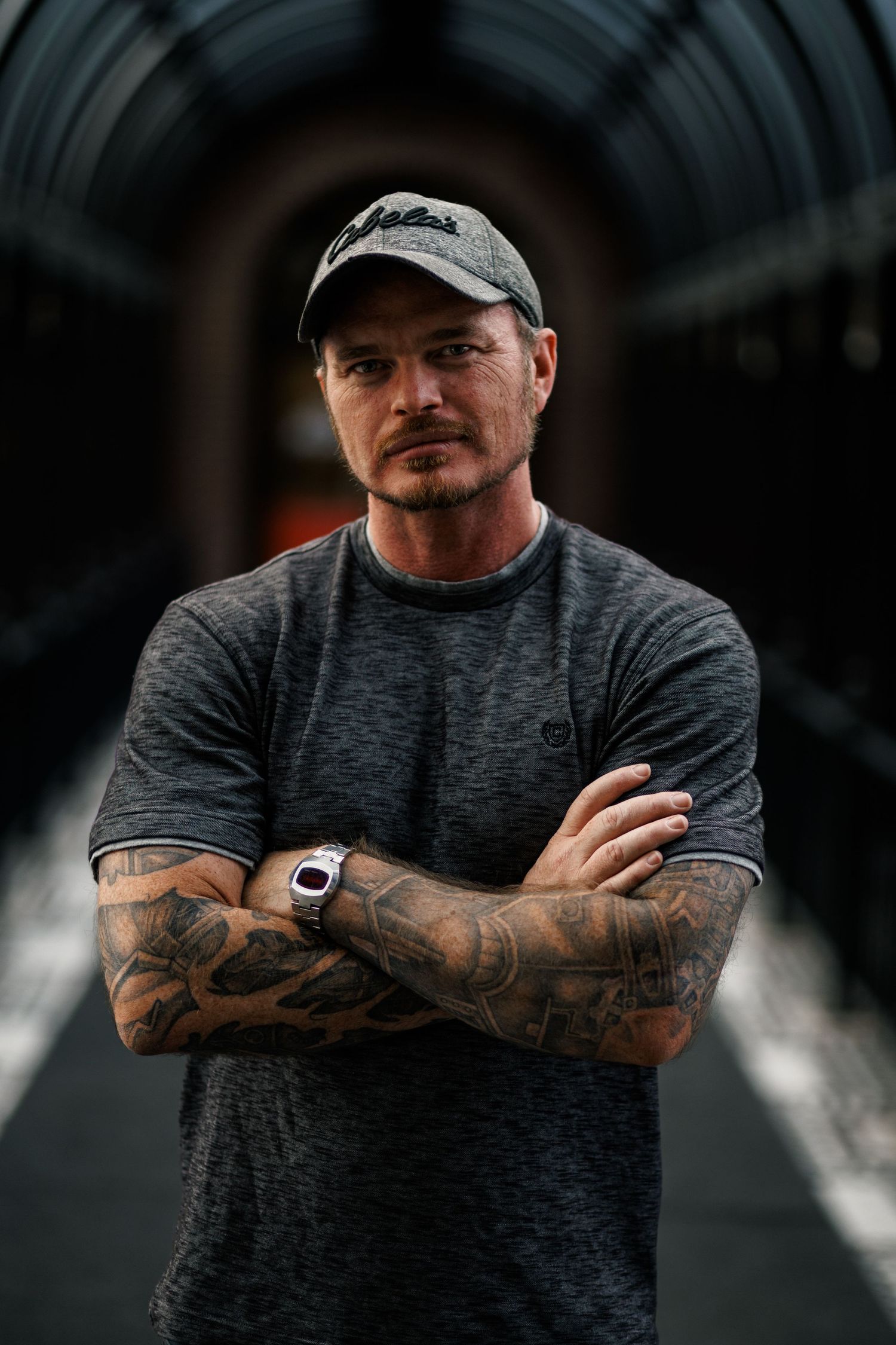 Person wearing a grey t-shirt and baseball cap showing tattooed arms in a series of close-up shots.