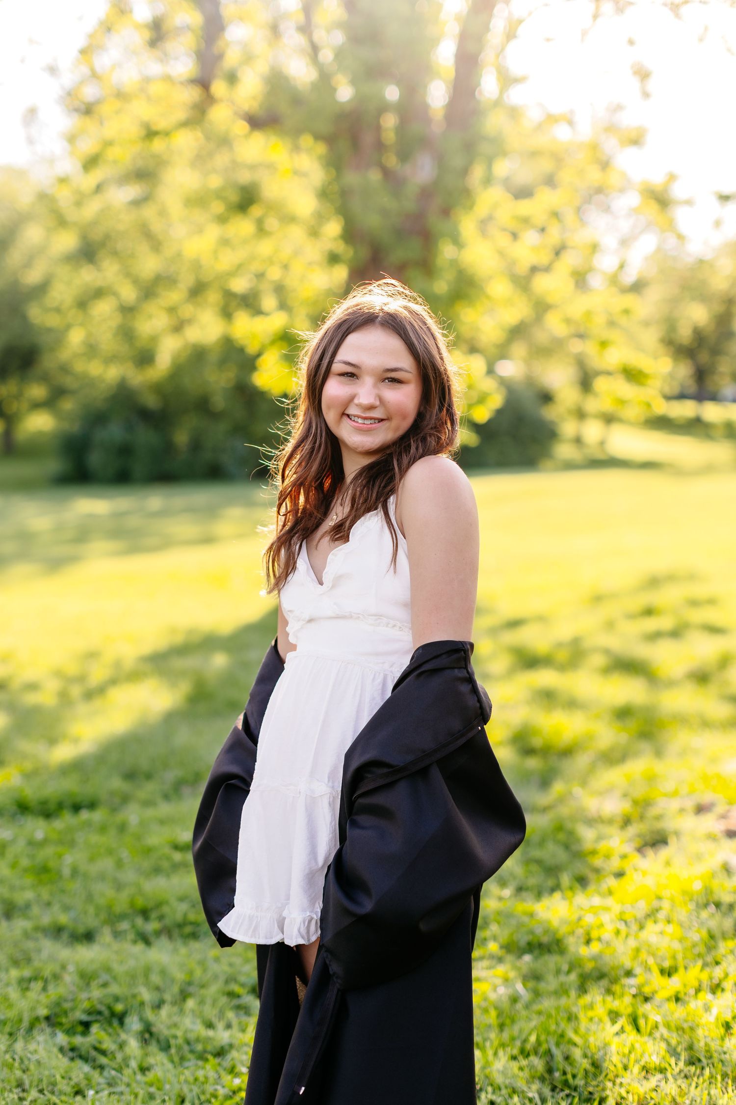 A joyful moment captured in a white dress and black cardigan on a sunny spring day in a green park setting.