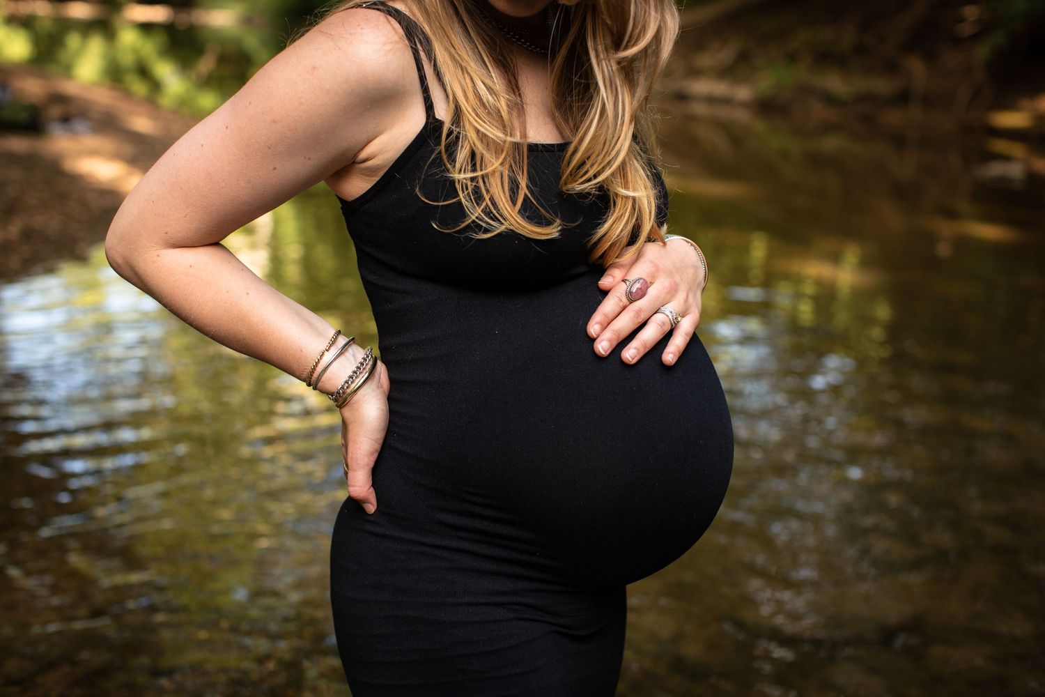 Close up maternity portrait highlighting intricate tattoo art and black dress.