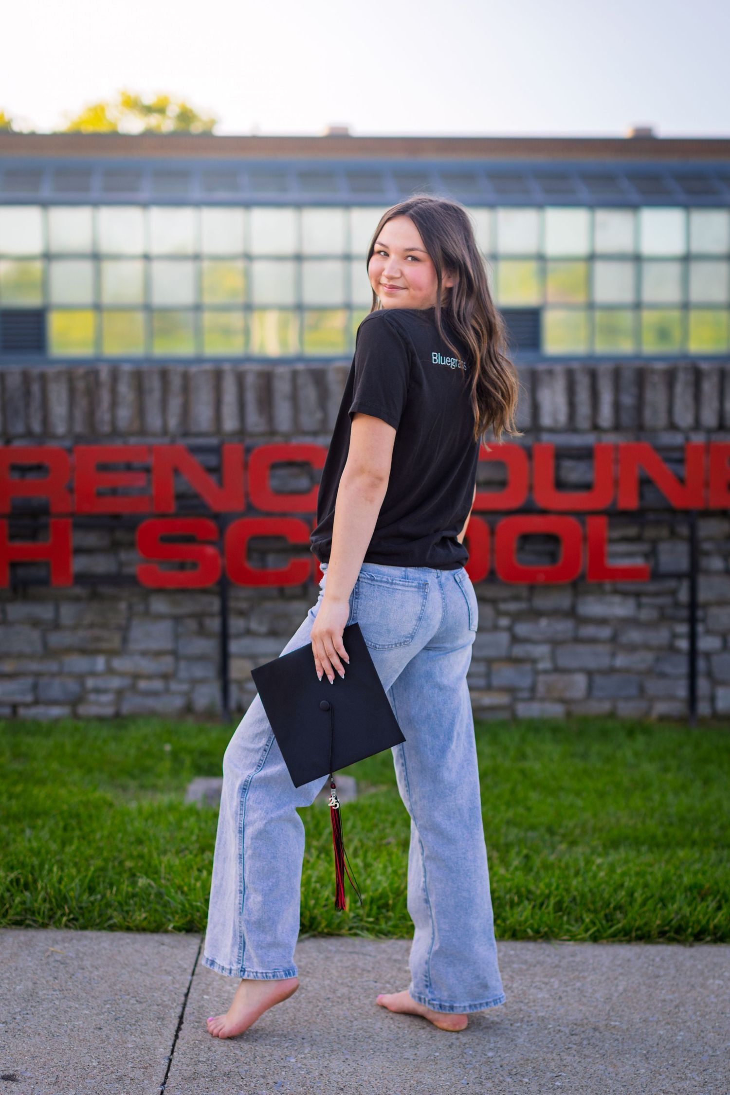 A toddler in a black shirt and light jeans stands against an industrial wall with red lettering.