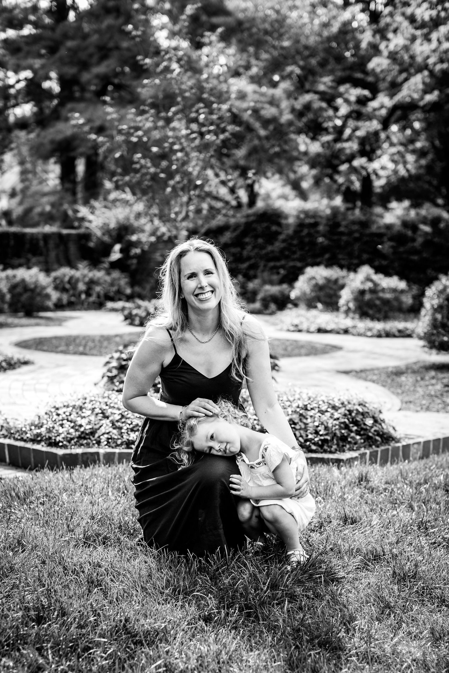 A candid black and white photo series showing a tender moment between a mother and child laying in grass outdoors.