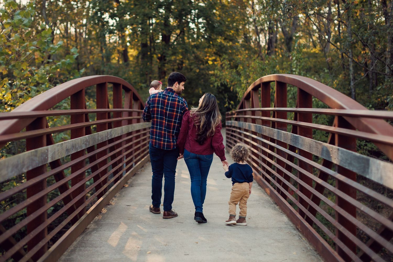 A series of photos showing people walking together on a wooden bridge surrounded by autumn foliage in a park setting.