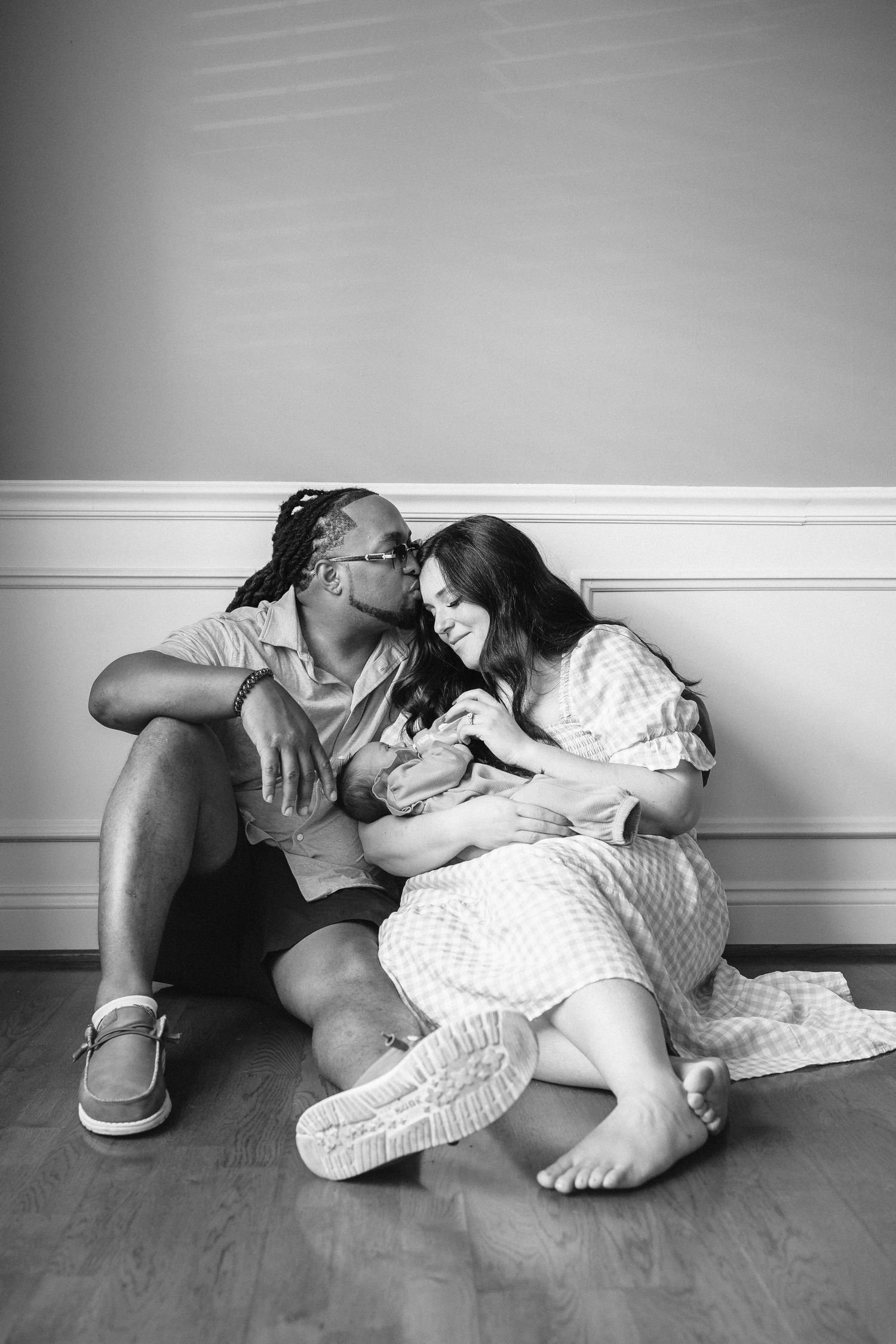 A black and white photo sequence showing intimate moments of maternal connection on a wooden floor.