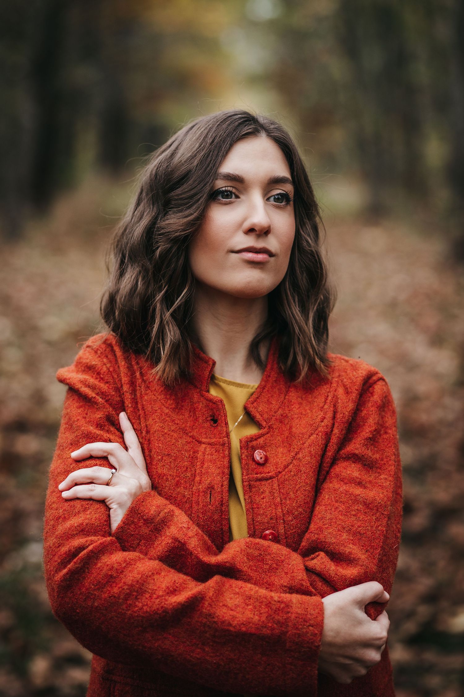Autumn portrait featuring bright red wool coat and mustard yellow top against fall foliage.