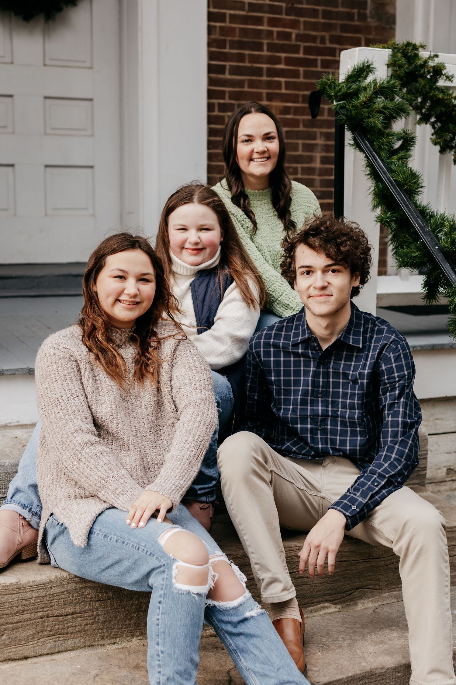 Group sitting on brick building steps in casual sweaters and jeans.