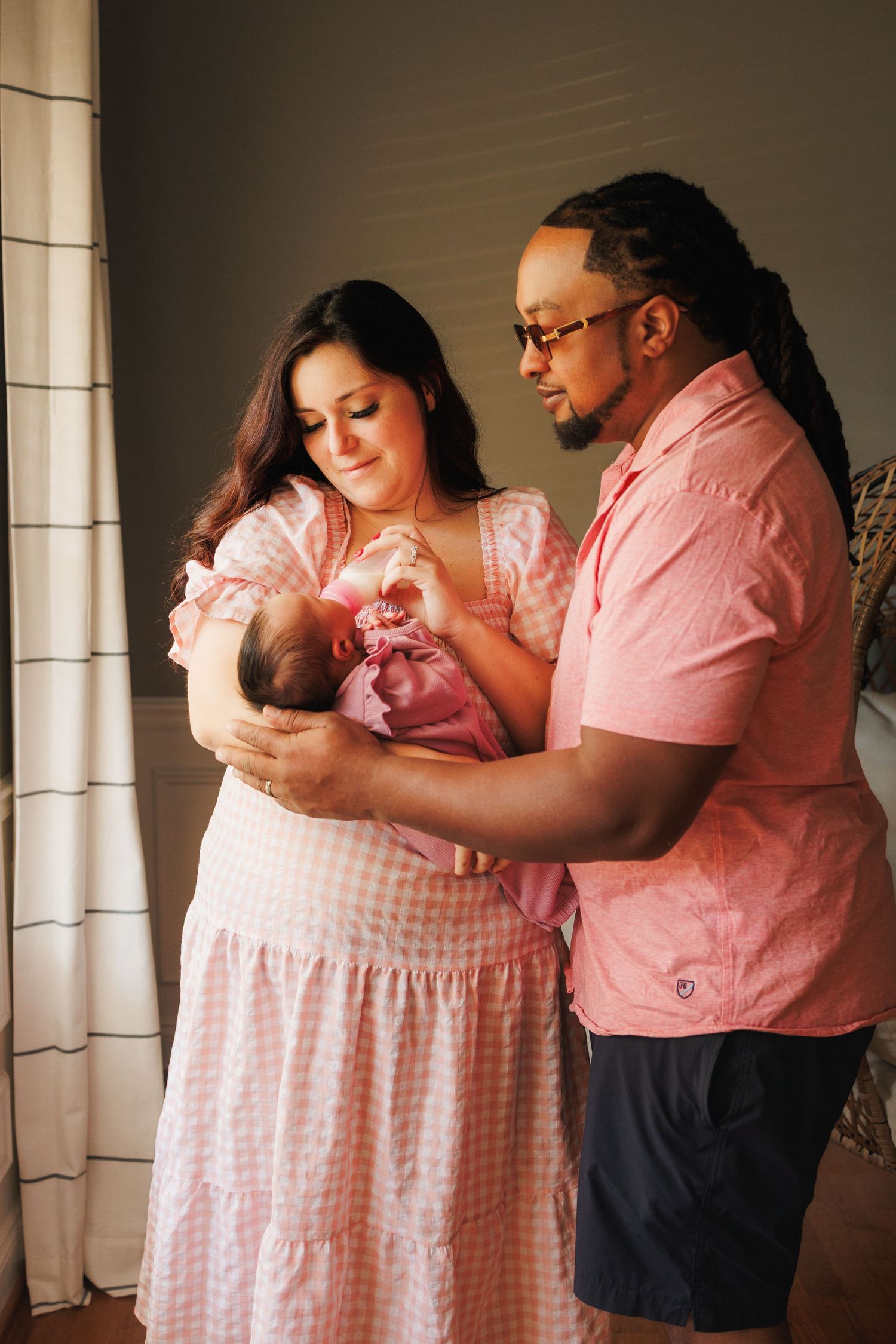 A series of intimate family photos showing parents tenderly holding and bonding with their newborn baby in pink tones.