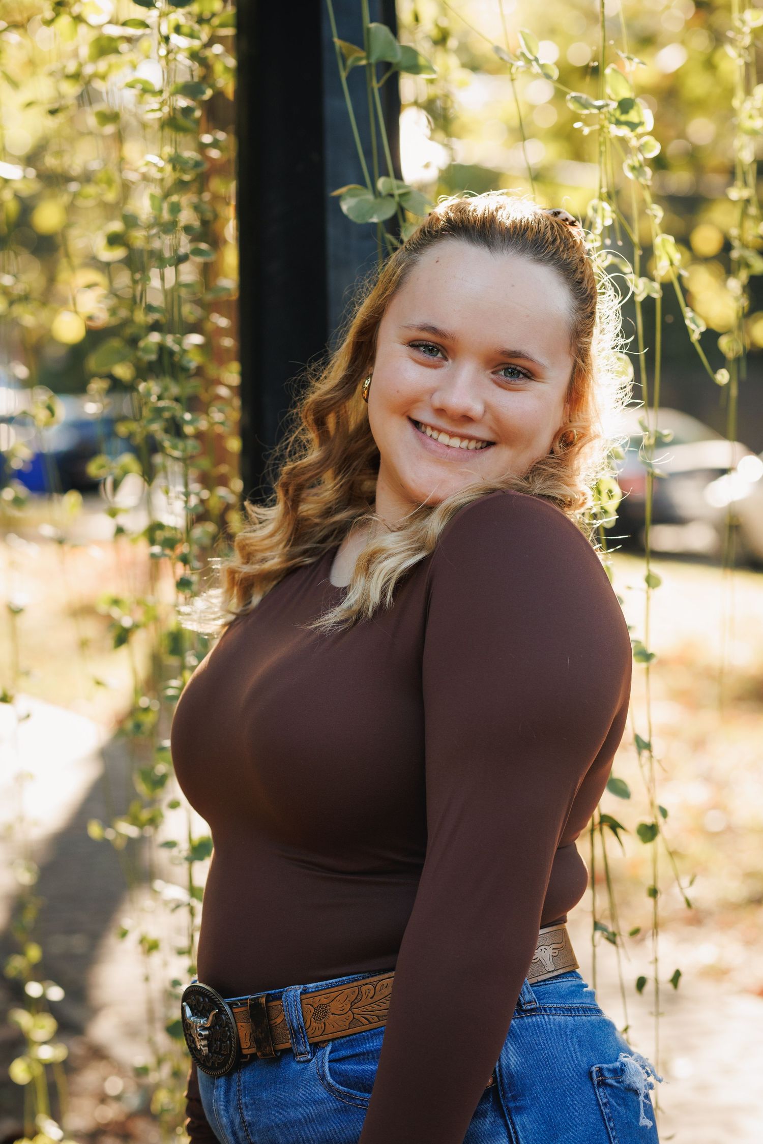 A portrait taken outdoors with warm sunlit bokeh and autumn foliage in the background.