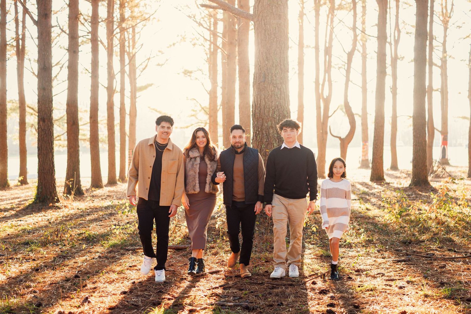 A group walks through a misty autumn forest with golden sunlight streaming through tall trees.