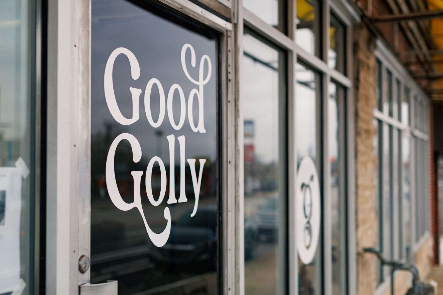 A storefront window displays the text 'Good' and 'Golly' in white lettering against a dark background.