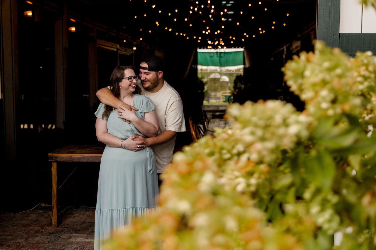 A romantic moment captured under soft lighting with hydrangeas in the foreground at an evening event.