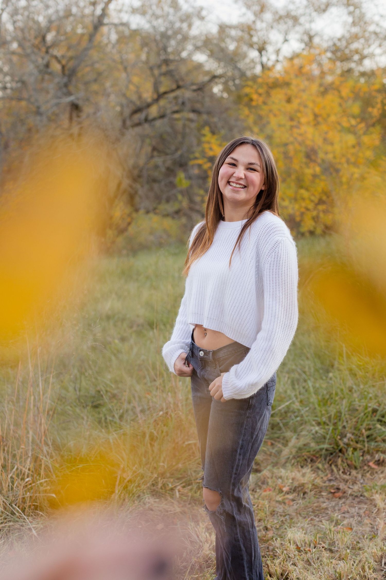 Autumn portrait in white sweater with golden bokeh leaves in foreground.