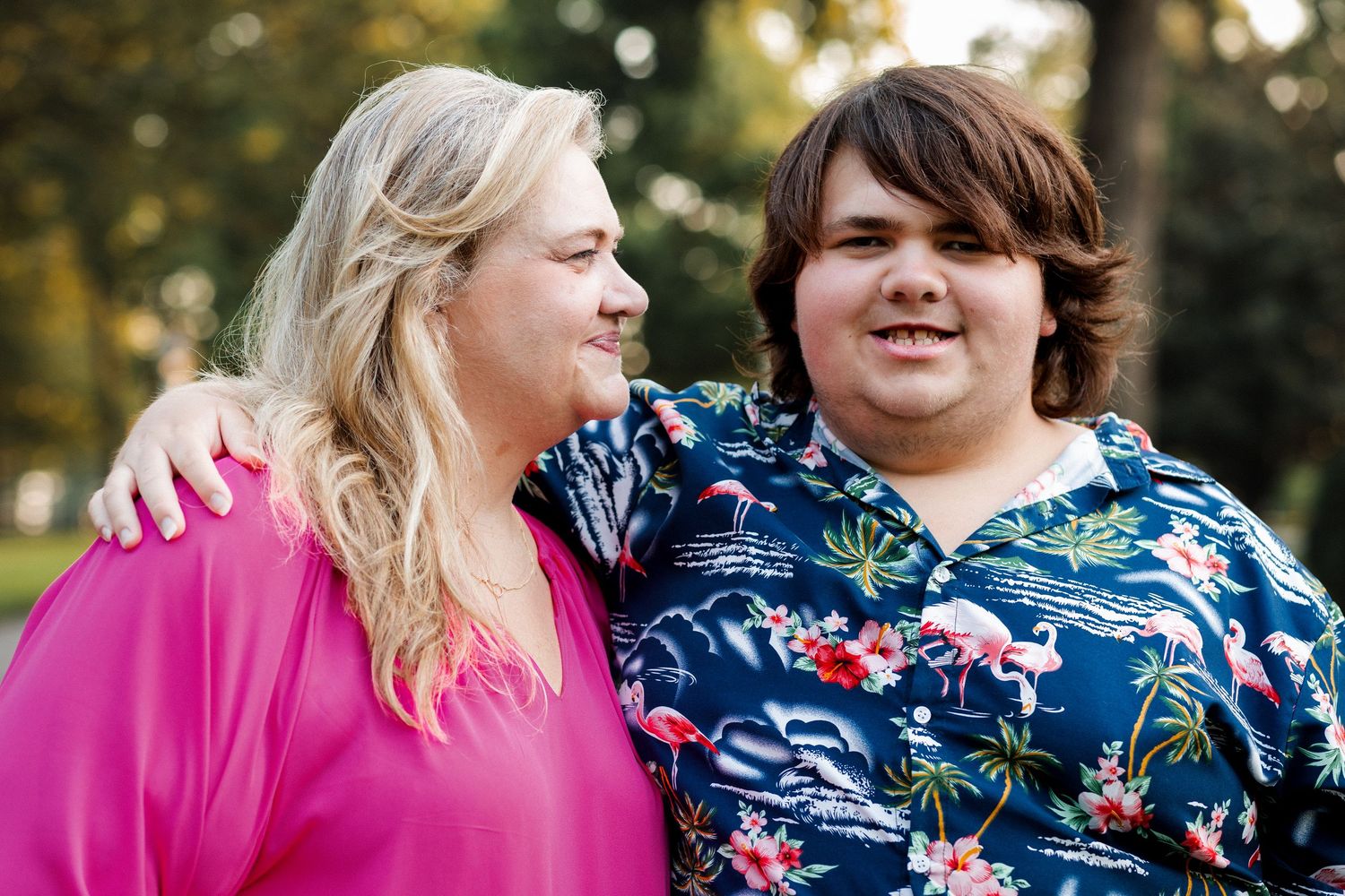 Two people wearing floral print clothing share a joyful moment together outdoors in natural lighting.