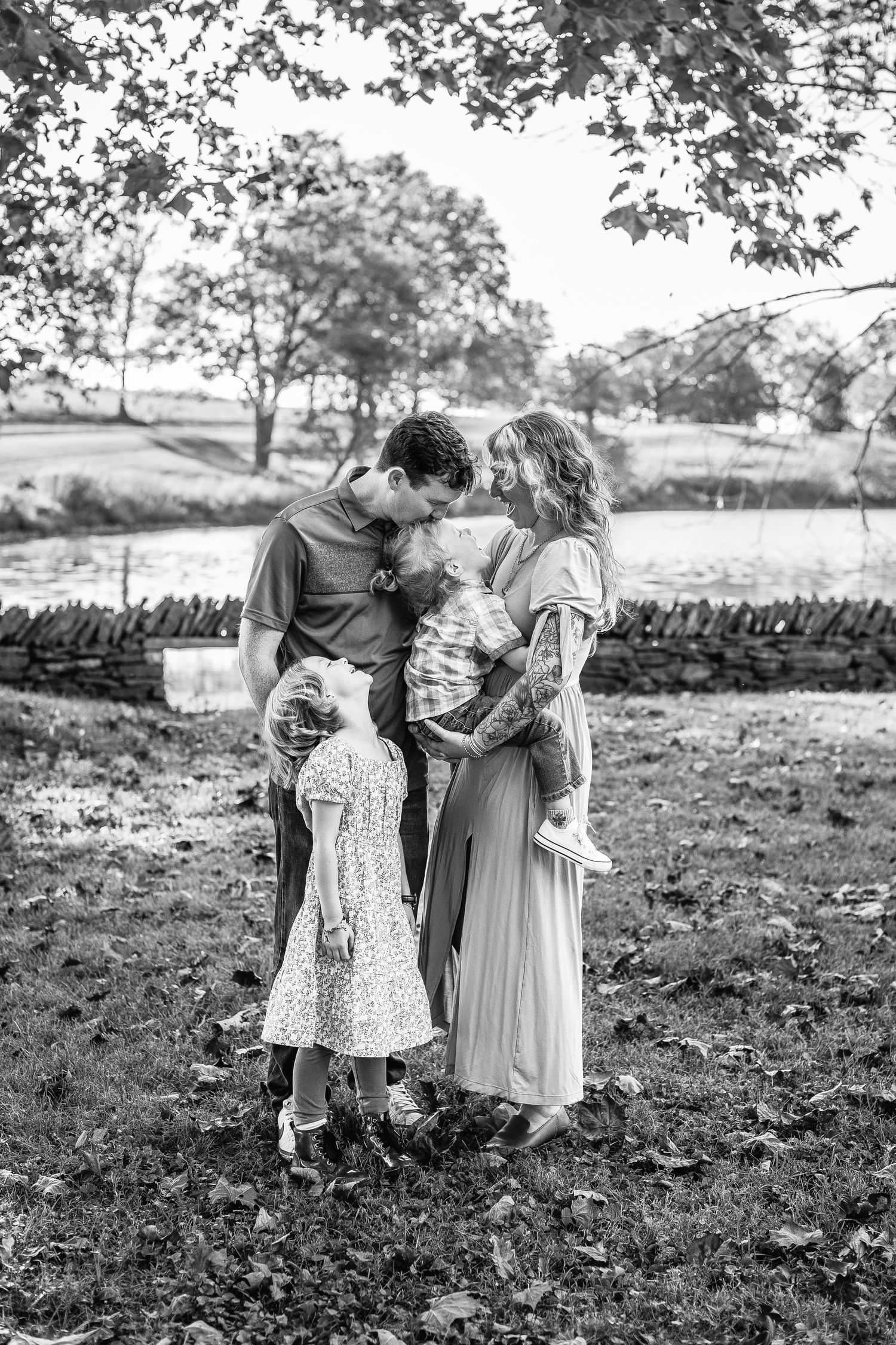 A black and white series of candid moments showing a family walking together outdoors in a natural setting.
