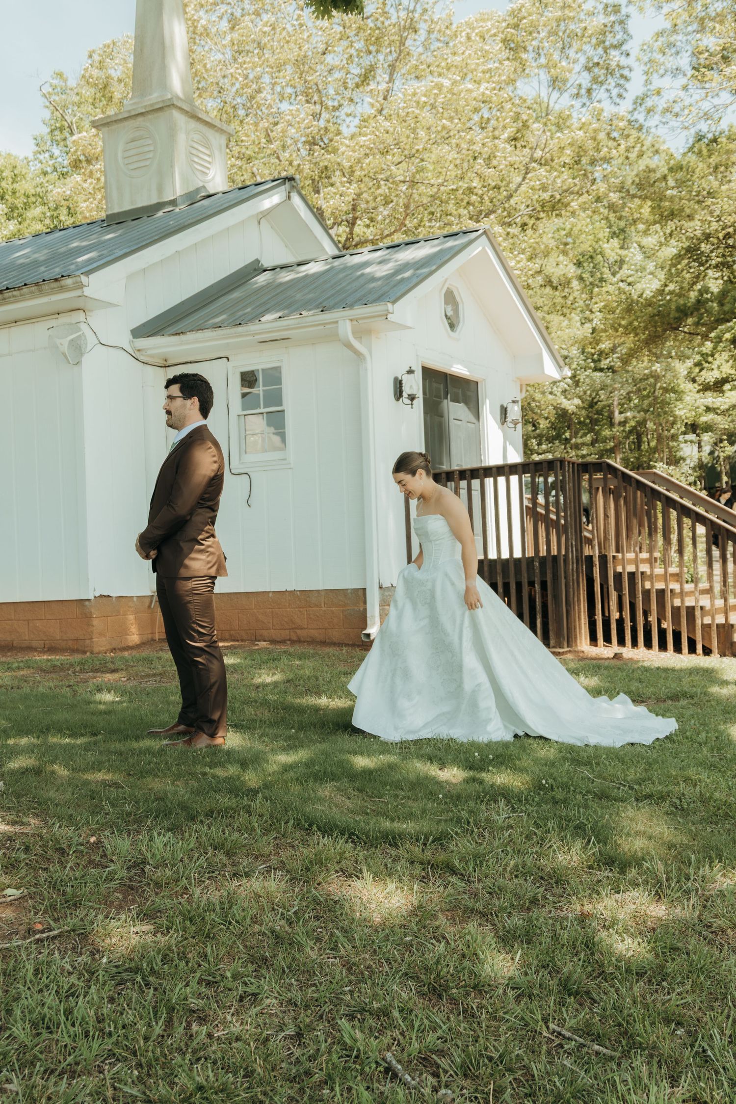 First look wedding moment outside a white chapel with bride and groom.