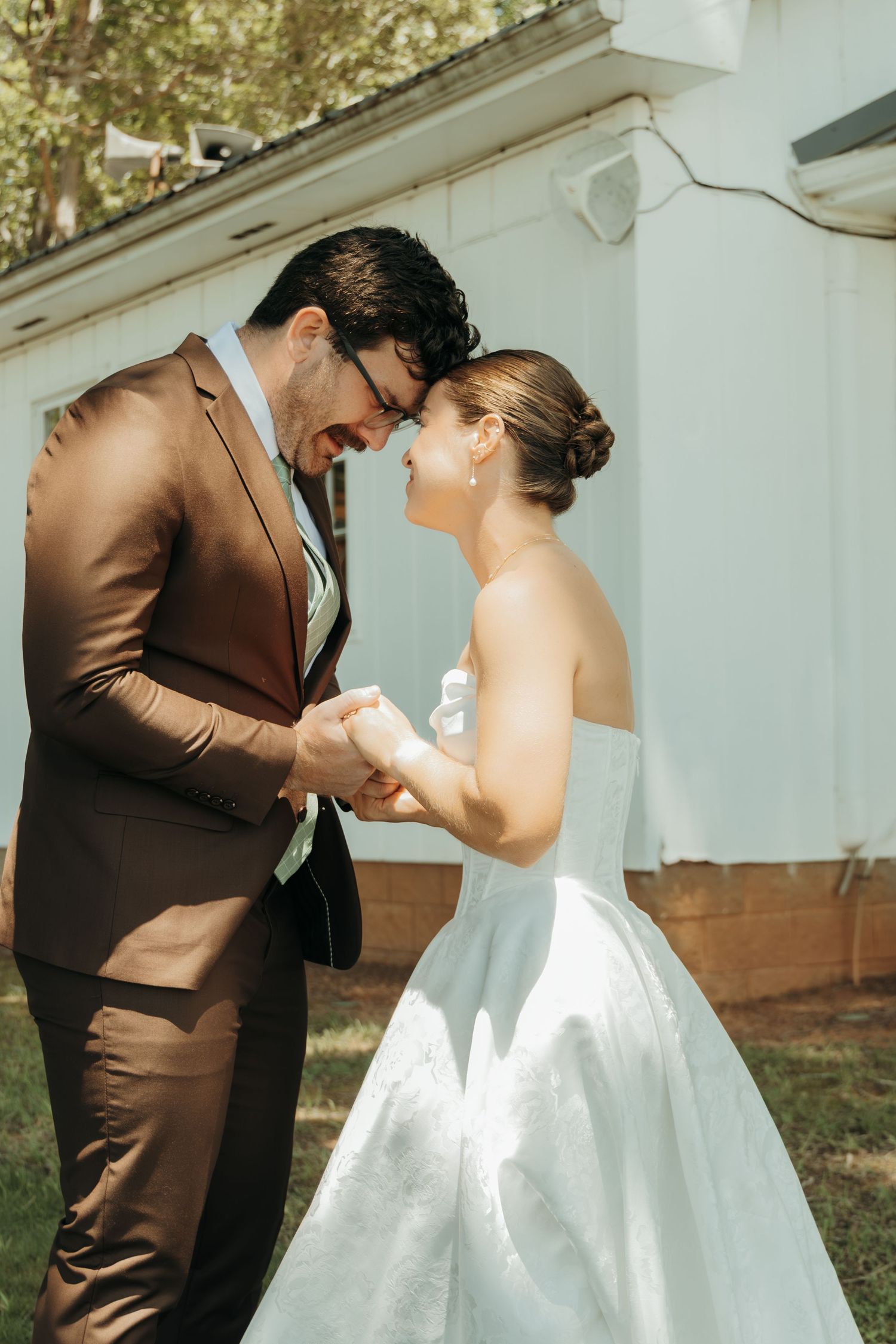 Intimate candid moment shared between couple in formal attire by white chapel.