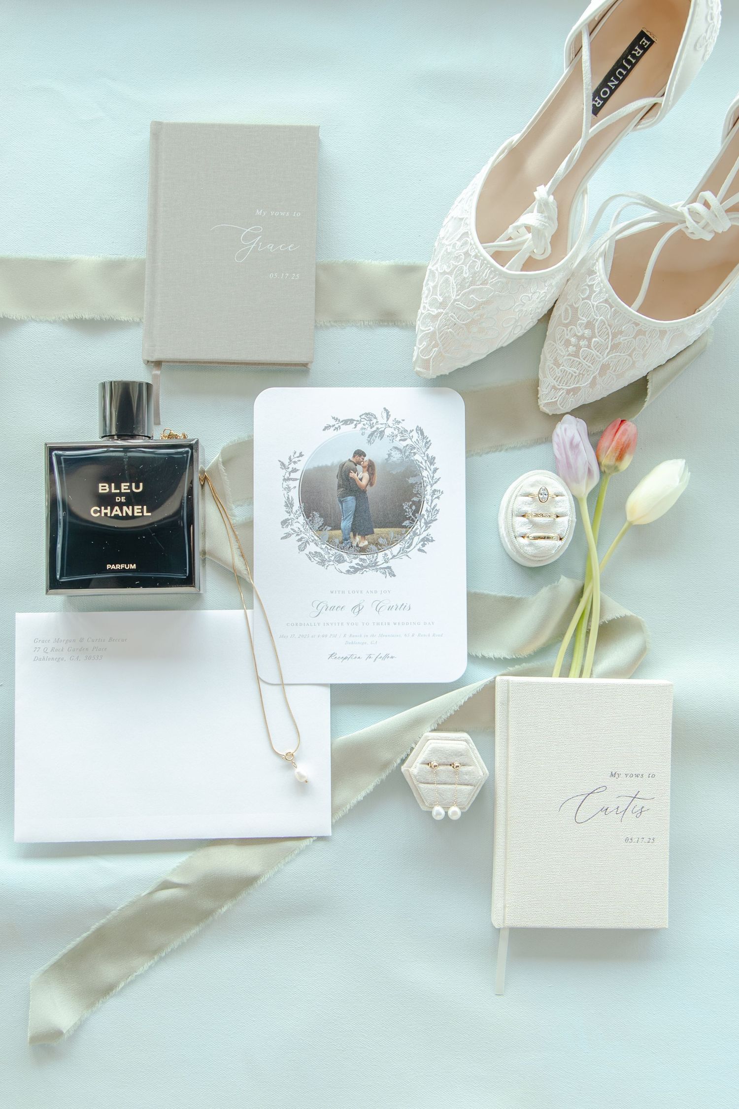 Wedding details flatlay with lace shoes, perfume, invitation card, jewelry and tulips on light background.