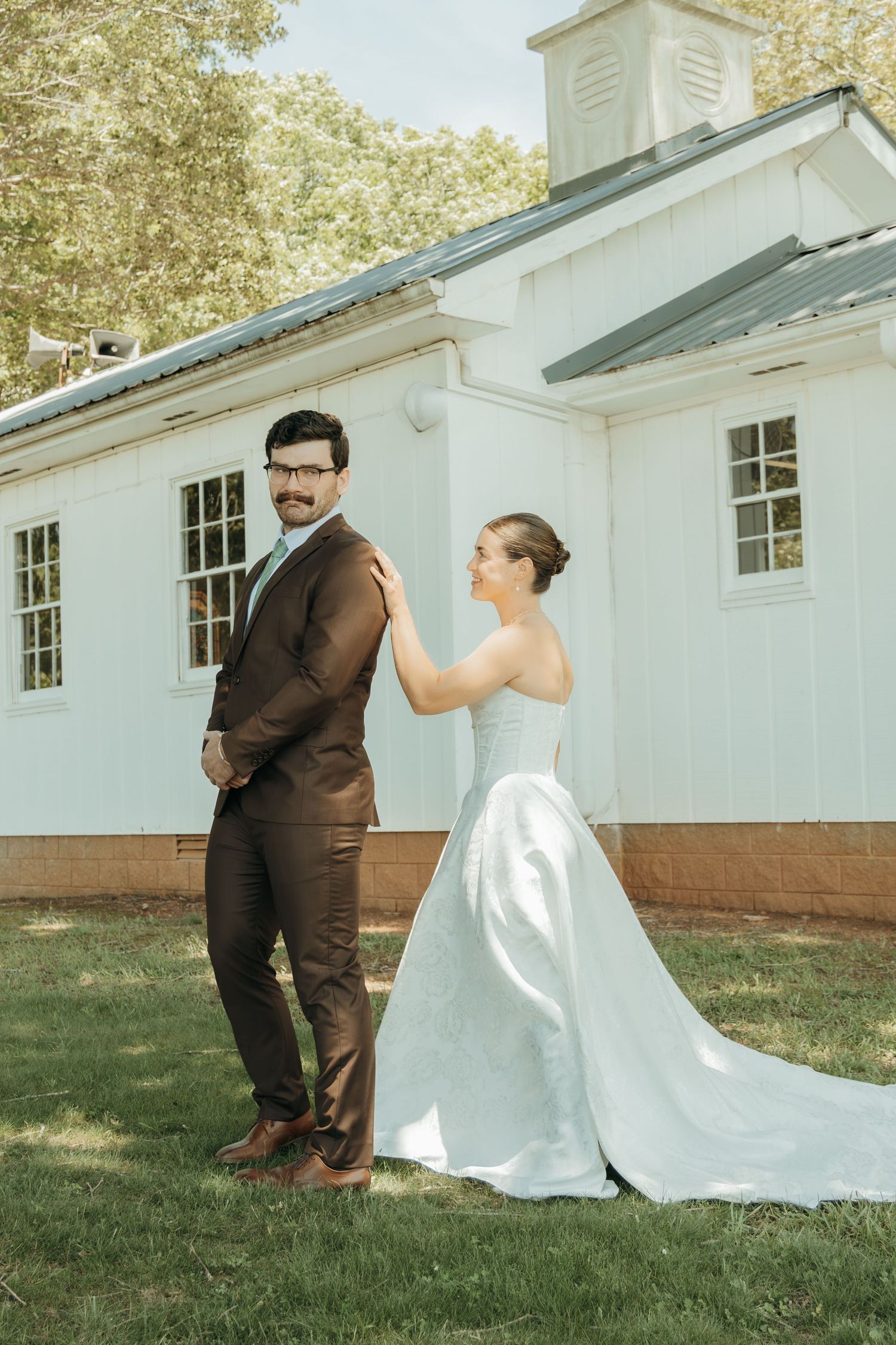 Bride and groom sharing a moment outside white chapel during first look photo session.