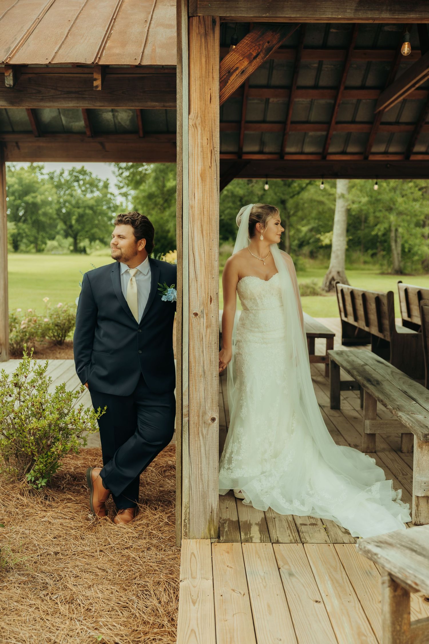 A romantic first look moment captured on a rustic wooden porch surrounded by greenery.