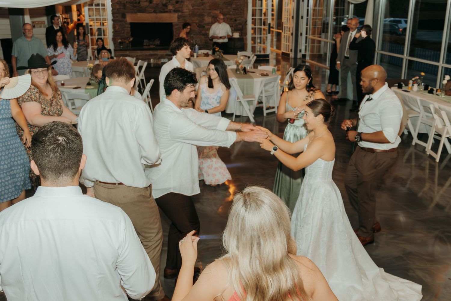 Wedding party members dancing in a line during reception with gray and white color scheme.