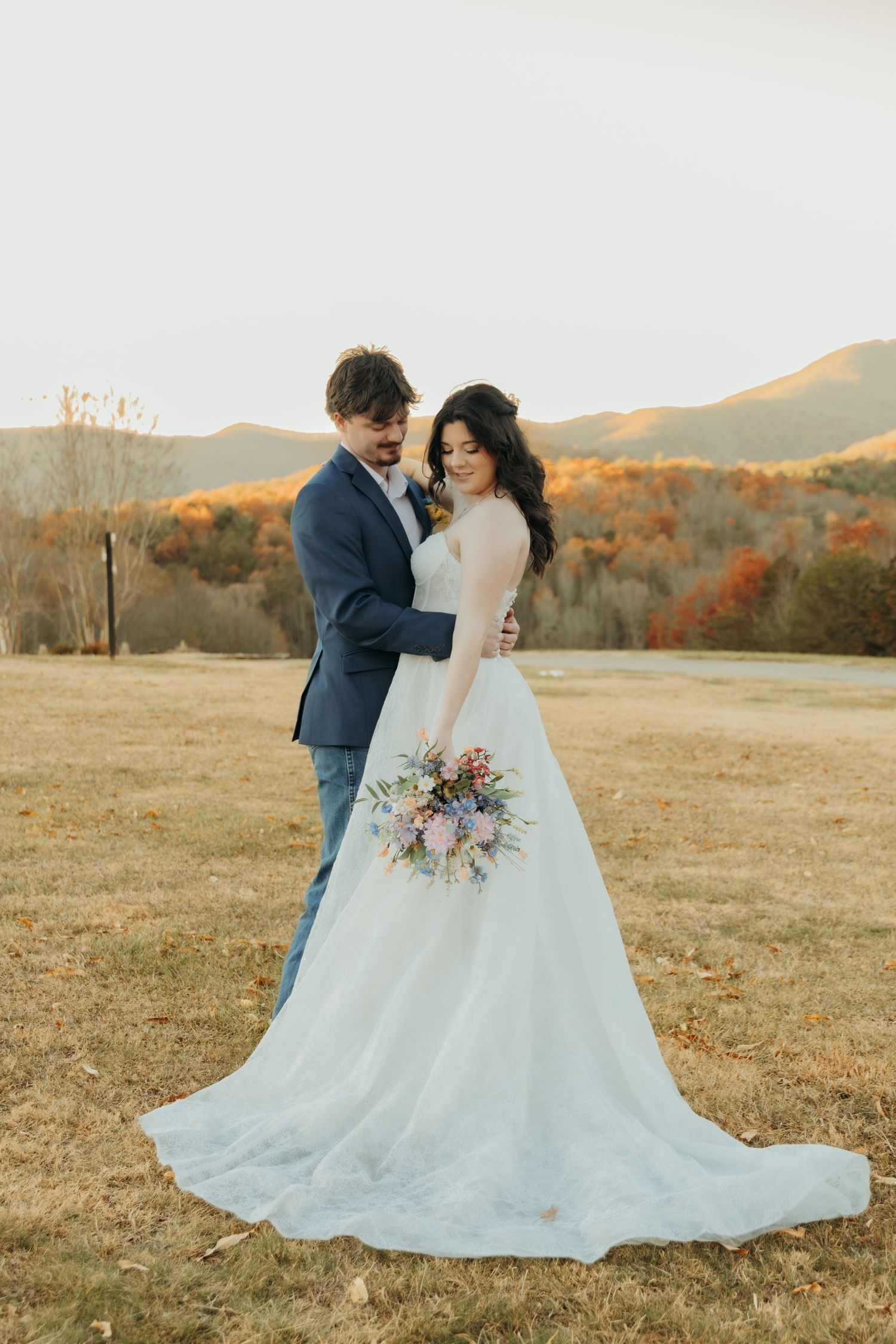 A romantic fall wedding photo shoot in a golden meadow with mountains and autumn foliage in the background.